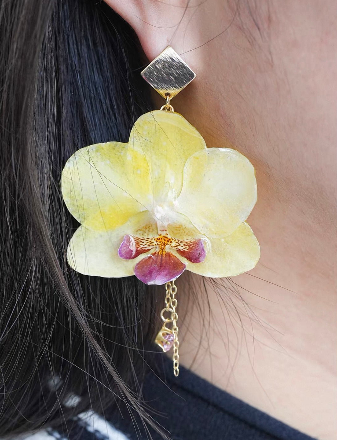 Butter Yellow orchid earrings with resin petals worn on ear by Terra Decode