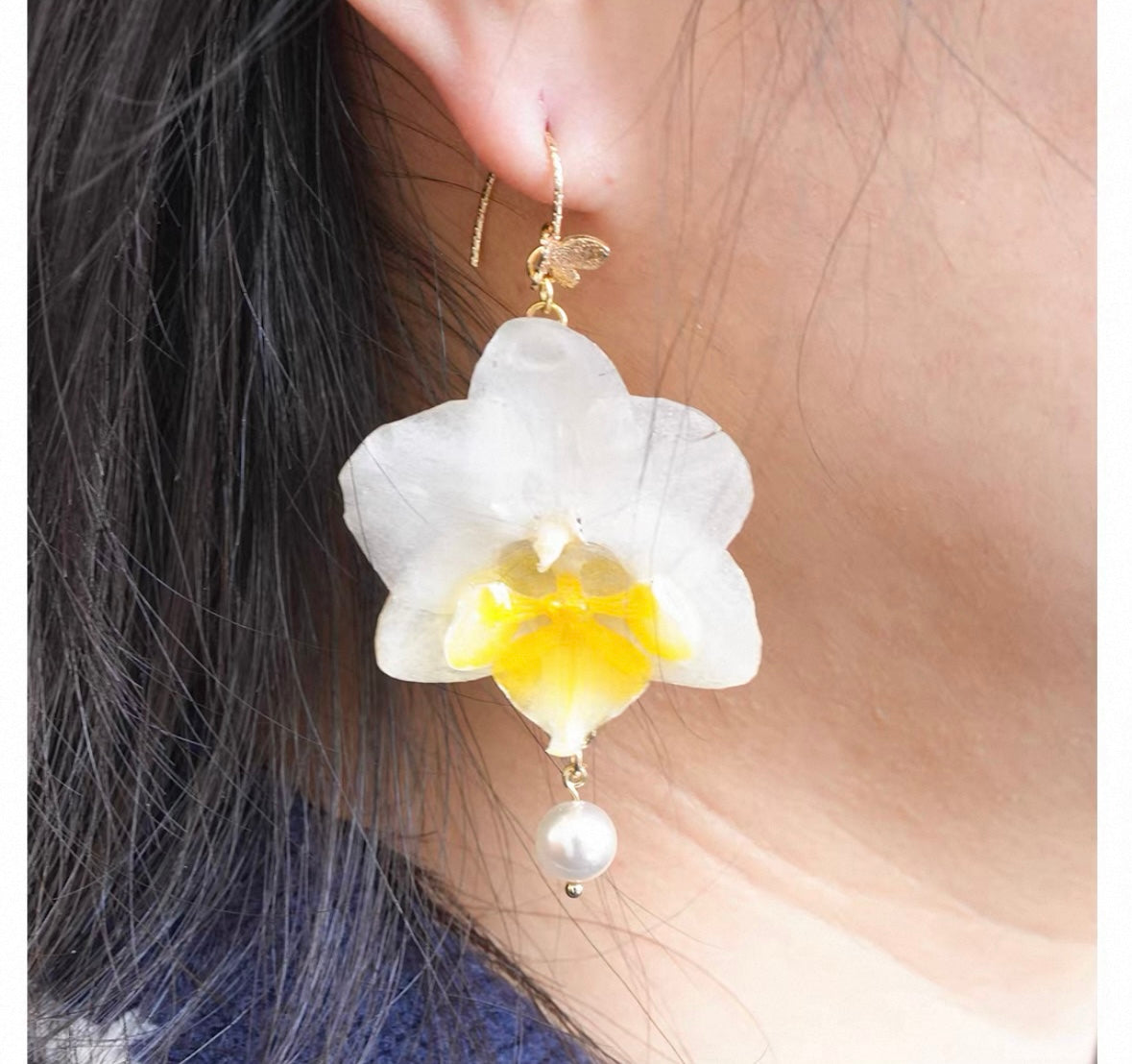 Cream White orchid earrings with resin petals worn on ear by Terra Decode