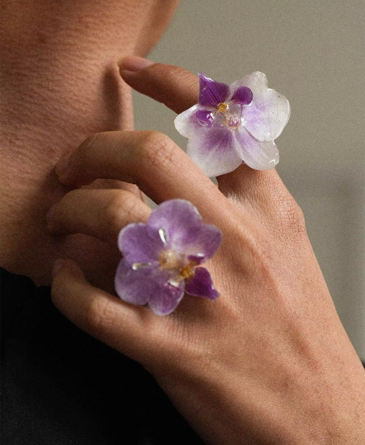 Soft purple and cream white orchid statement rings with resin petals worn near face by Terra Decode