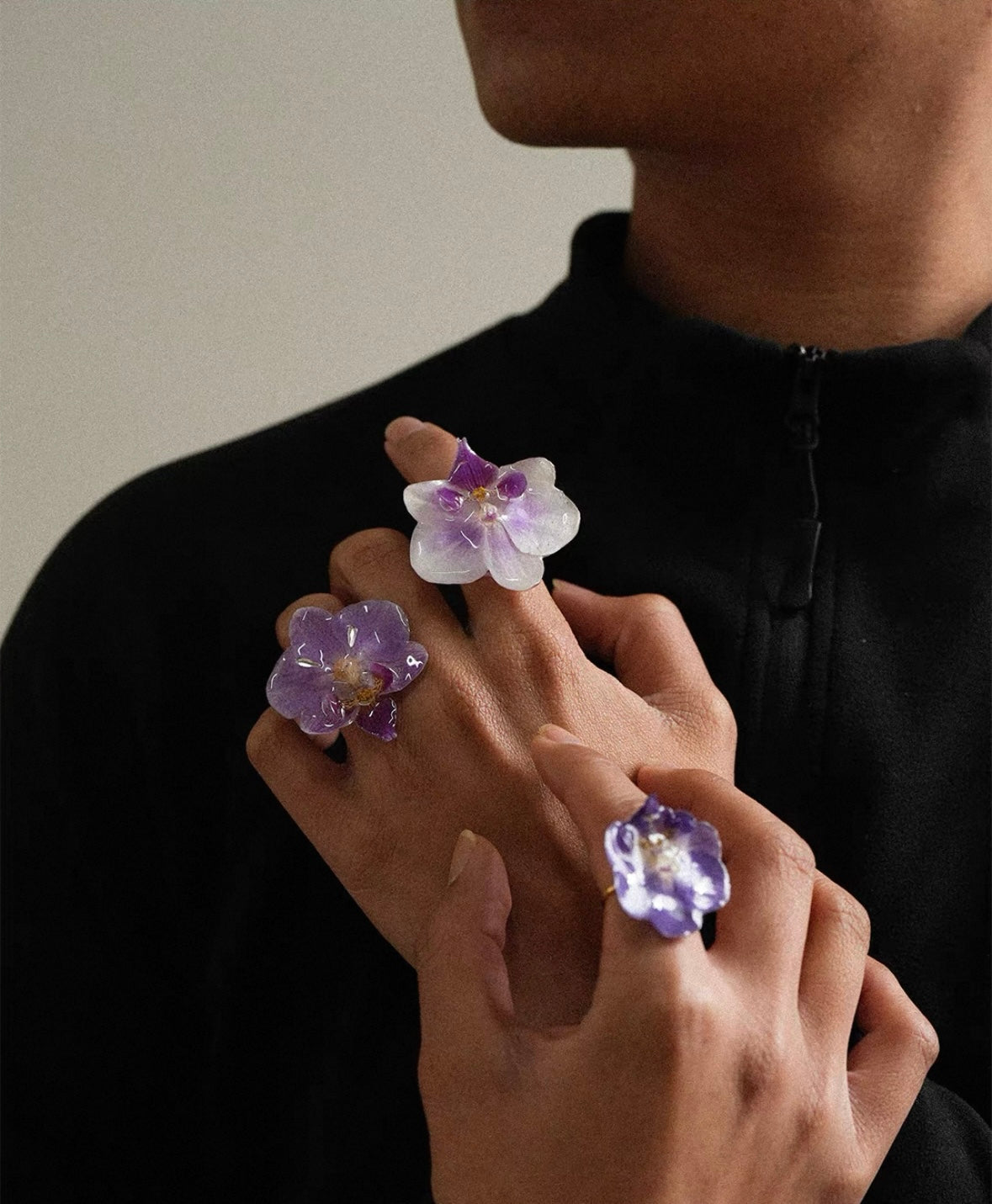 Orchid statement ring variations with resin petals worn on hand against black fabric by Terra Decode