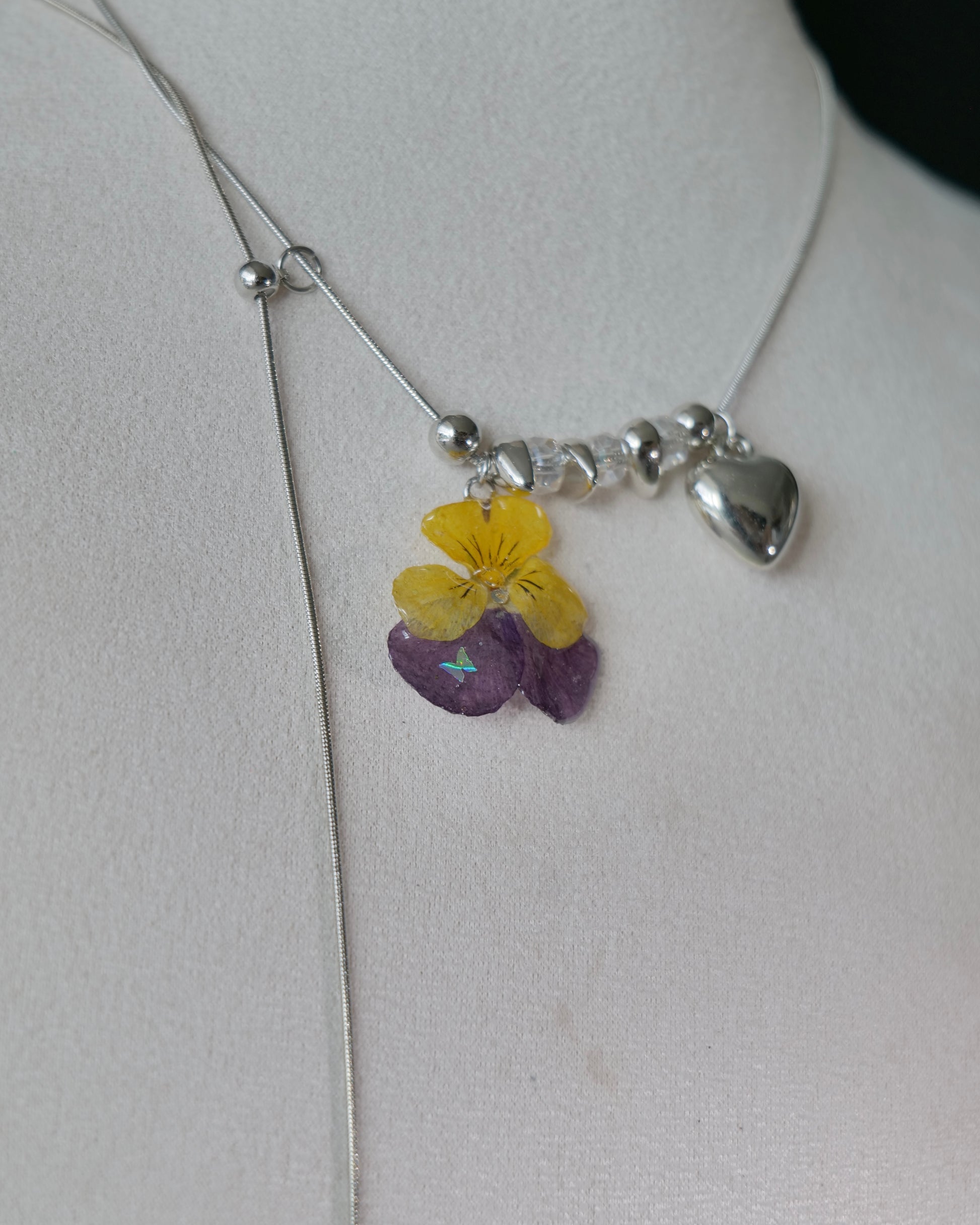 Natural-light view of preserved pansy necklace with sliding chain construction