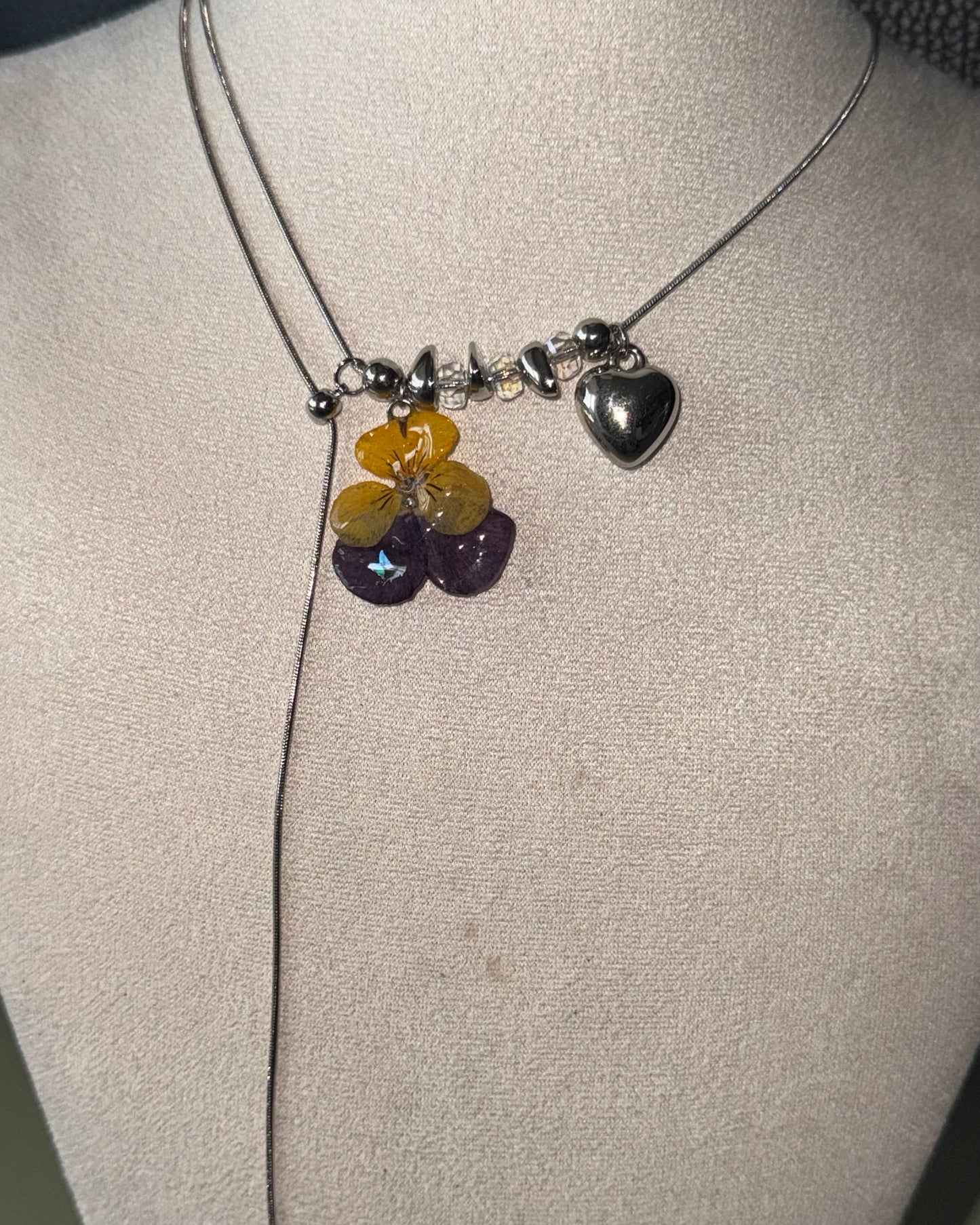 Reflective view of pansy pendant, clear bead accents and silver-toned heart charm
