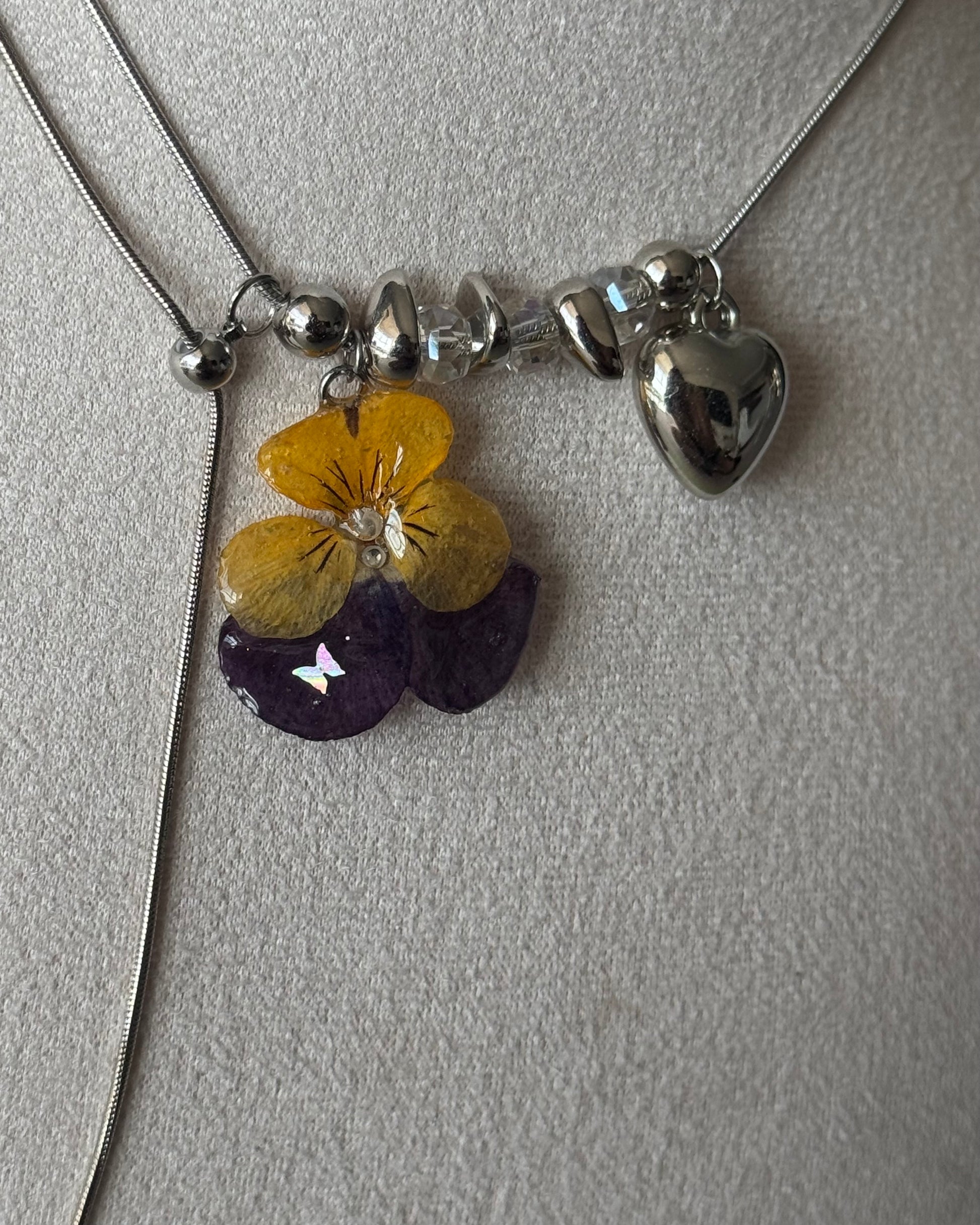 Close-up of yellow and purple pansy resin pendant with rounded bead accents