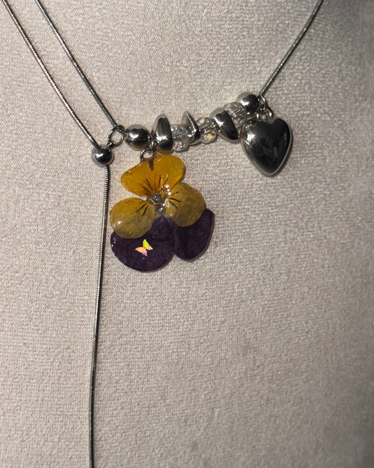 Detailed view of clear and silver-toned beads beside the pansy pendant