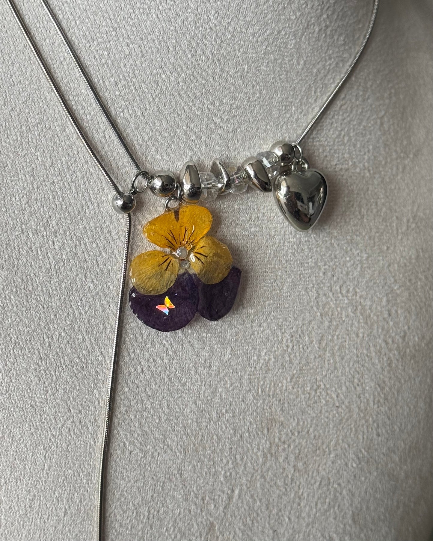 Angled close-up of yellow-and-purple pansy resin pendant