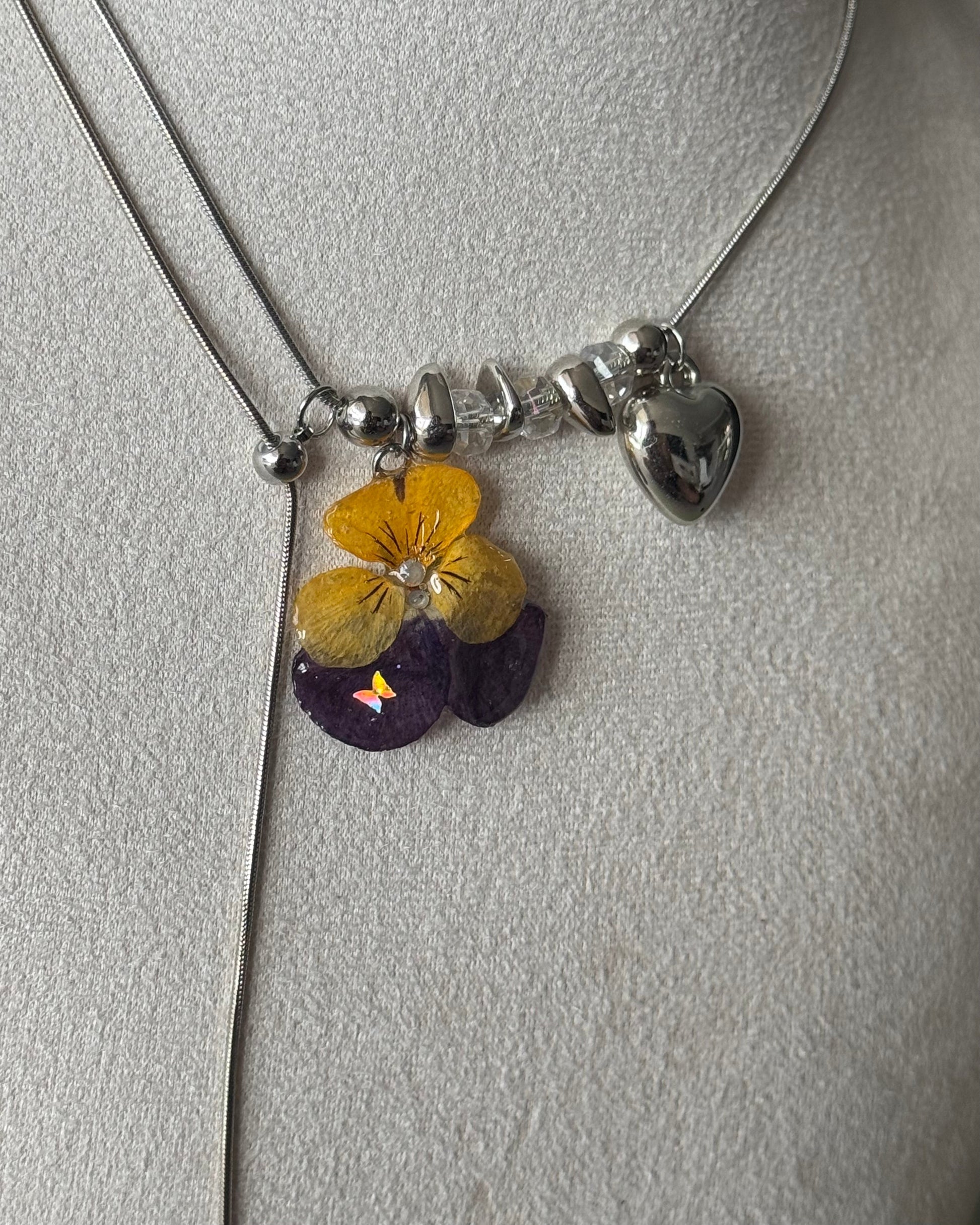 Angled close-up of yellow-and-purple pansy resin pendant