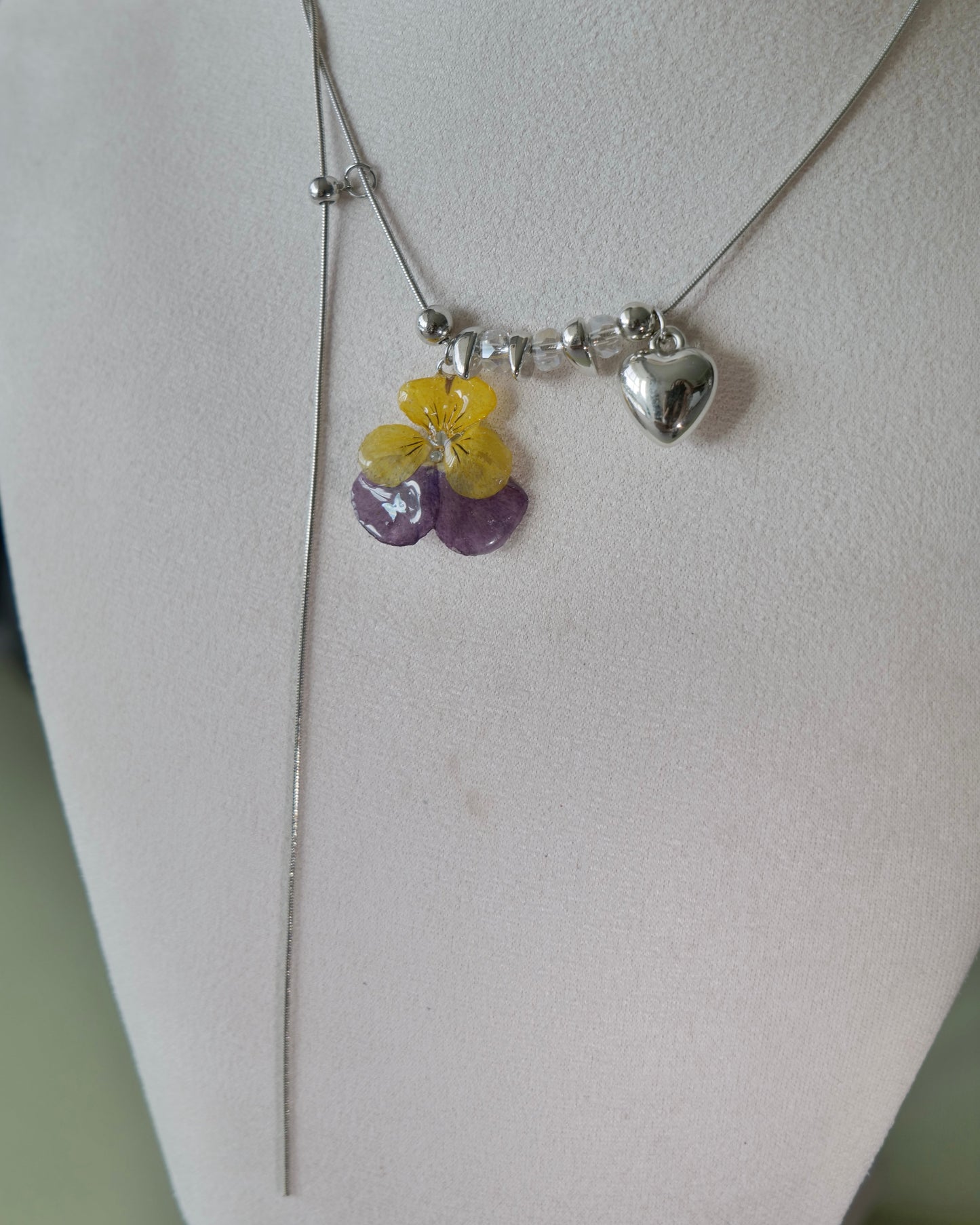 Natural-light angle of adjustable pansy lariat necklace on display