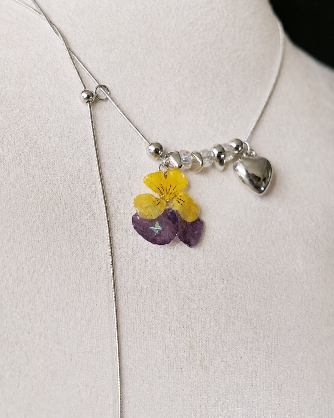 Detailed view of the Pansy Heart Adjustable Lariat Necklace on a cream jewellery bust, Pansy Heart Adjustable Lariat Necklace botanical jewellery by Terra Decode