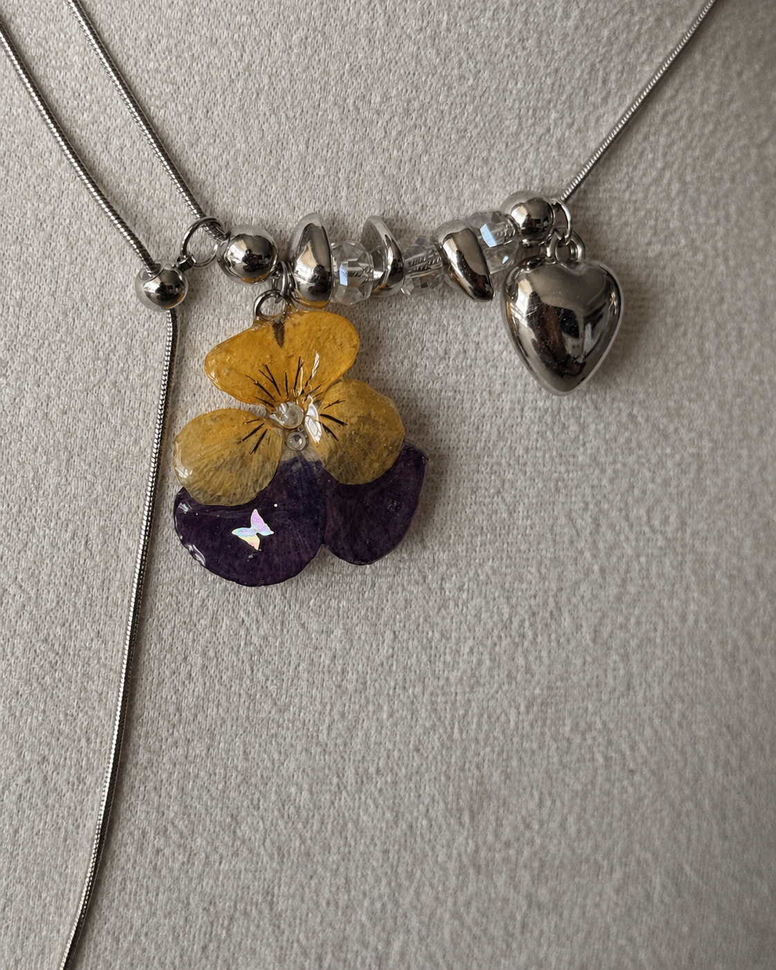 Reflective detail of the pansy pendant, clear bead accents and heart charm, Pansy Heart Adjustable Lariat Necklace botanical jewellery by Terra Decode