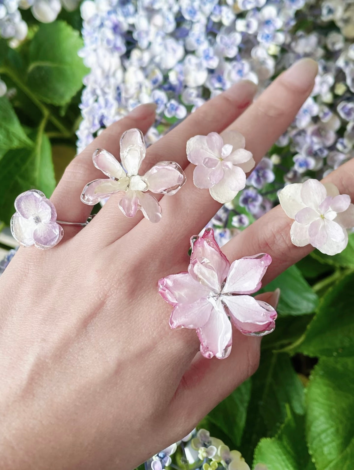 Hydrangea blue and soft pink hydrangea rings with resin petals worn among garden blooms by Terra Decode