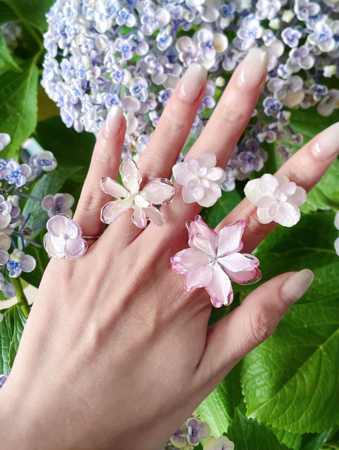Hydrangea ring variations with translucent resin petals worn against blooming hydrangeas by Terra Decode