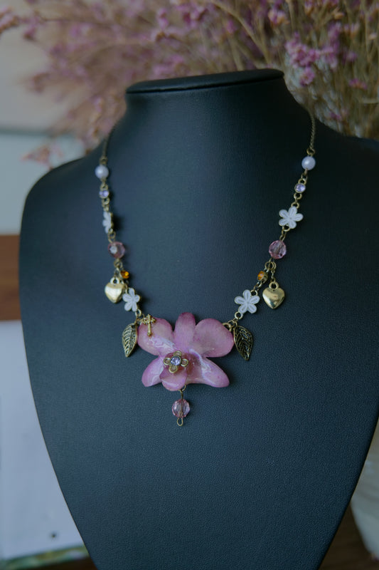 Front view of preserved Dendrobium orchid necklace with antique-gold heart, flower and leaf charms