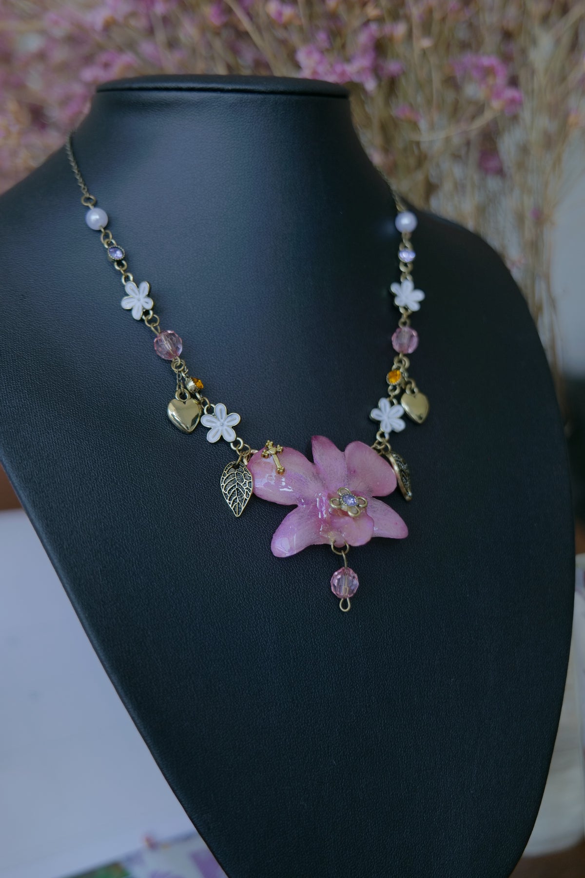Close-up of pink crystal and pearl-style details beside the preserved Dendrobium orchid