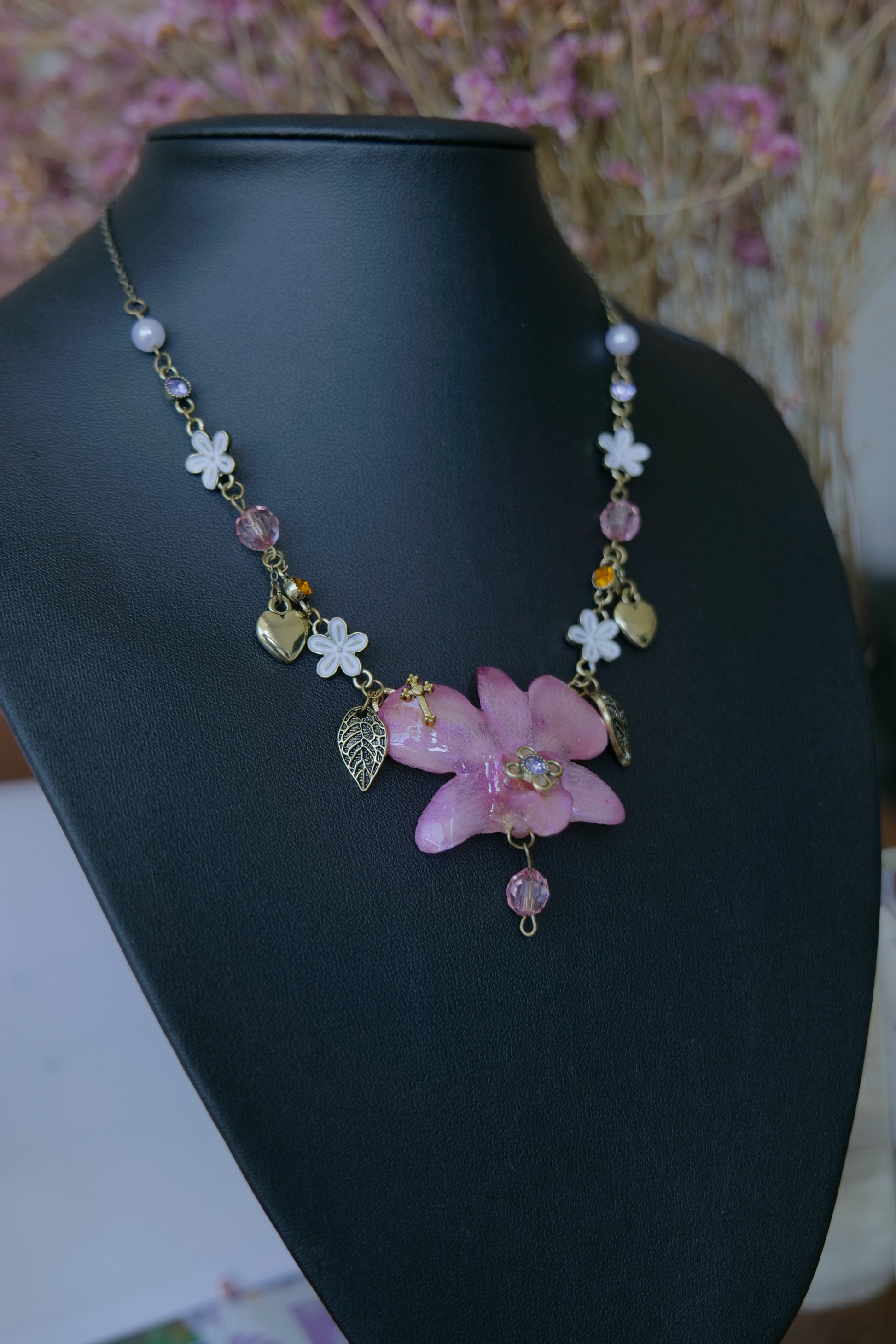 Close-up of pink crystal and pearl-style details beside the preserved Dendrobium orchid