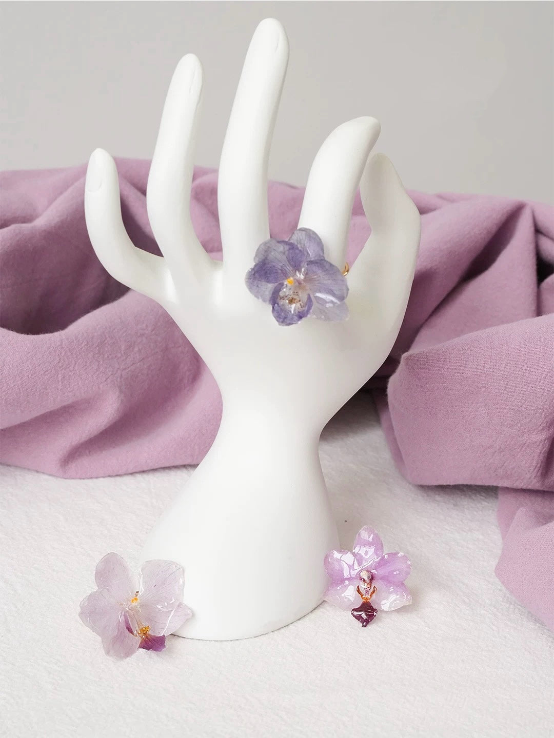 Lavender purple orchid ring with resin petals displayed on a hand form by Terra Decode