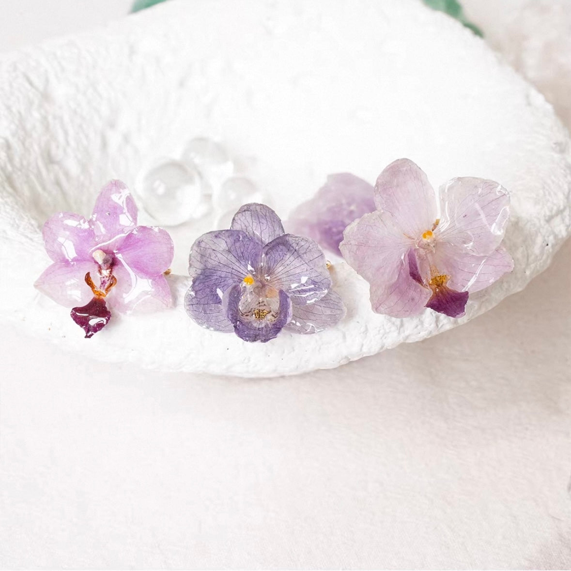 Soft purple orchid ring set with resin petals arranged on a white surface by Terra Decode