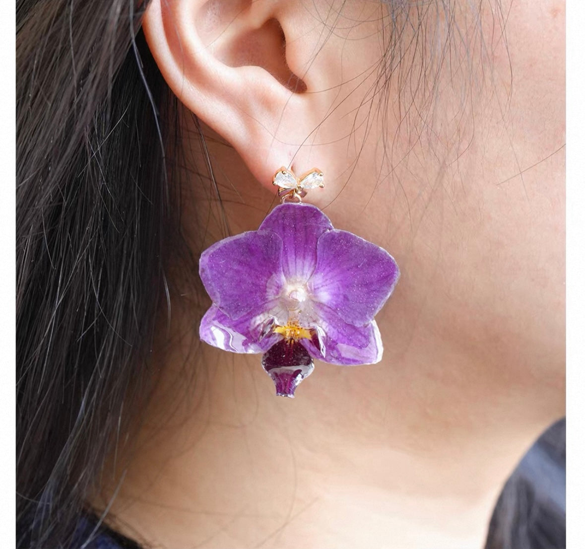 Purple Hook orchid earrings with resin petals worn on ear by Terra Decode