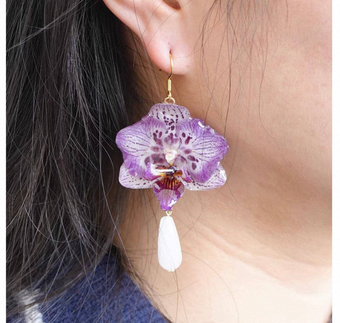 Purple teardrop orchid earrings with resin petals worn on ear by Terra Decode