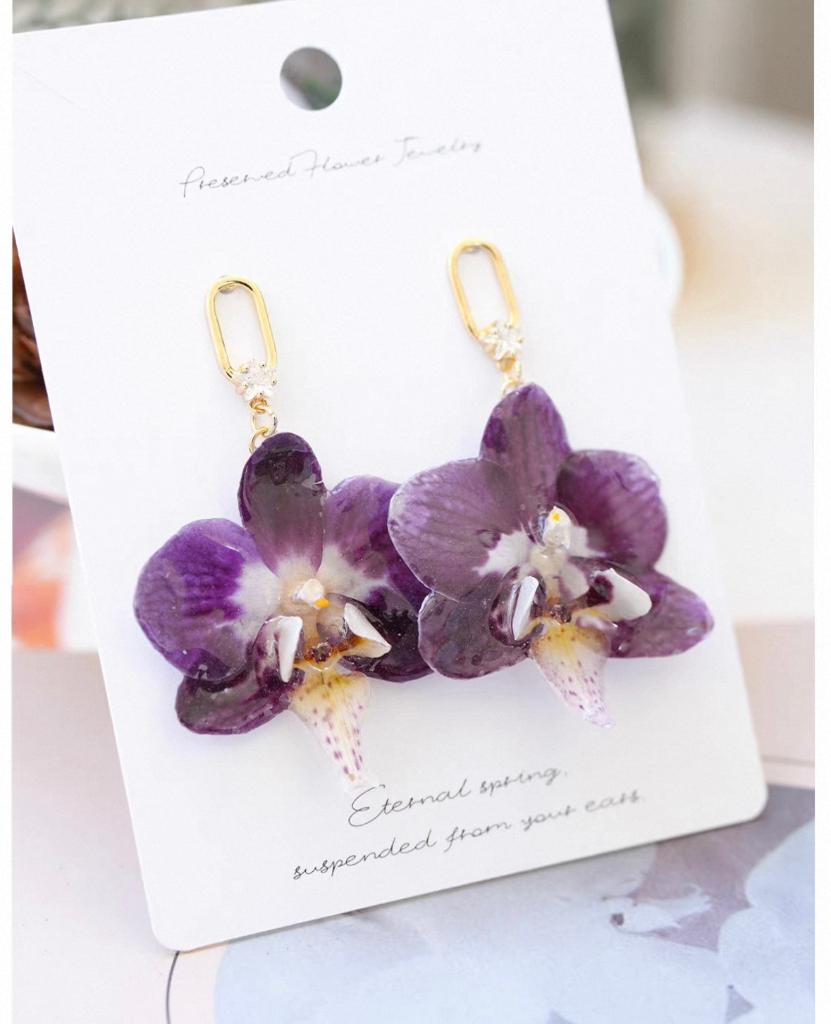 Purple orchid hook earrings with resin flower petals displayed on a jewellery card by Terra Decode
