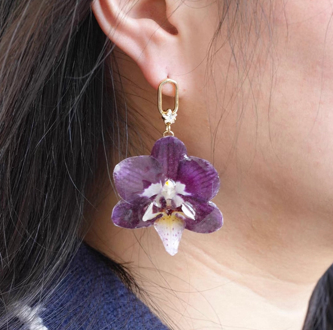 Purple orchid hook earring with resin petals and gold-tone link worn on ear by Terra Decode