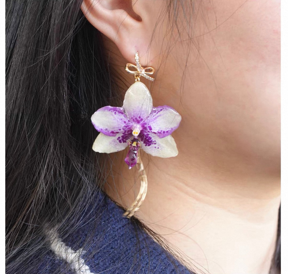 Bow chain detail orchid drop earring with resin petals and clear teardrop worn on ear by Terra Decode