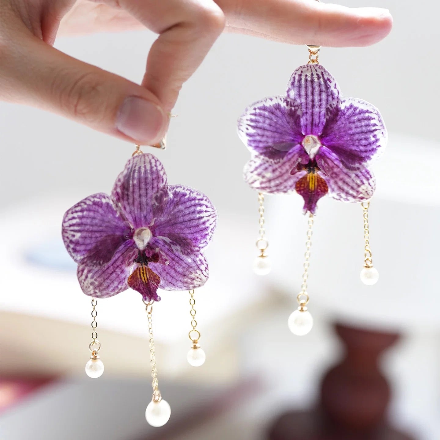 Purple orchid earrings with resin petals, chain detail and pearl-like drops by Terra Decode