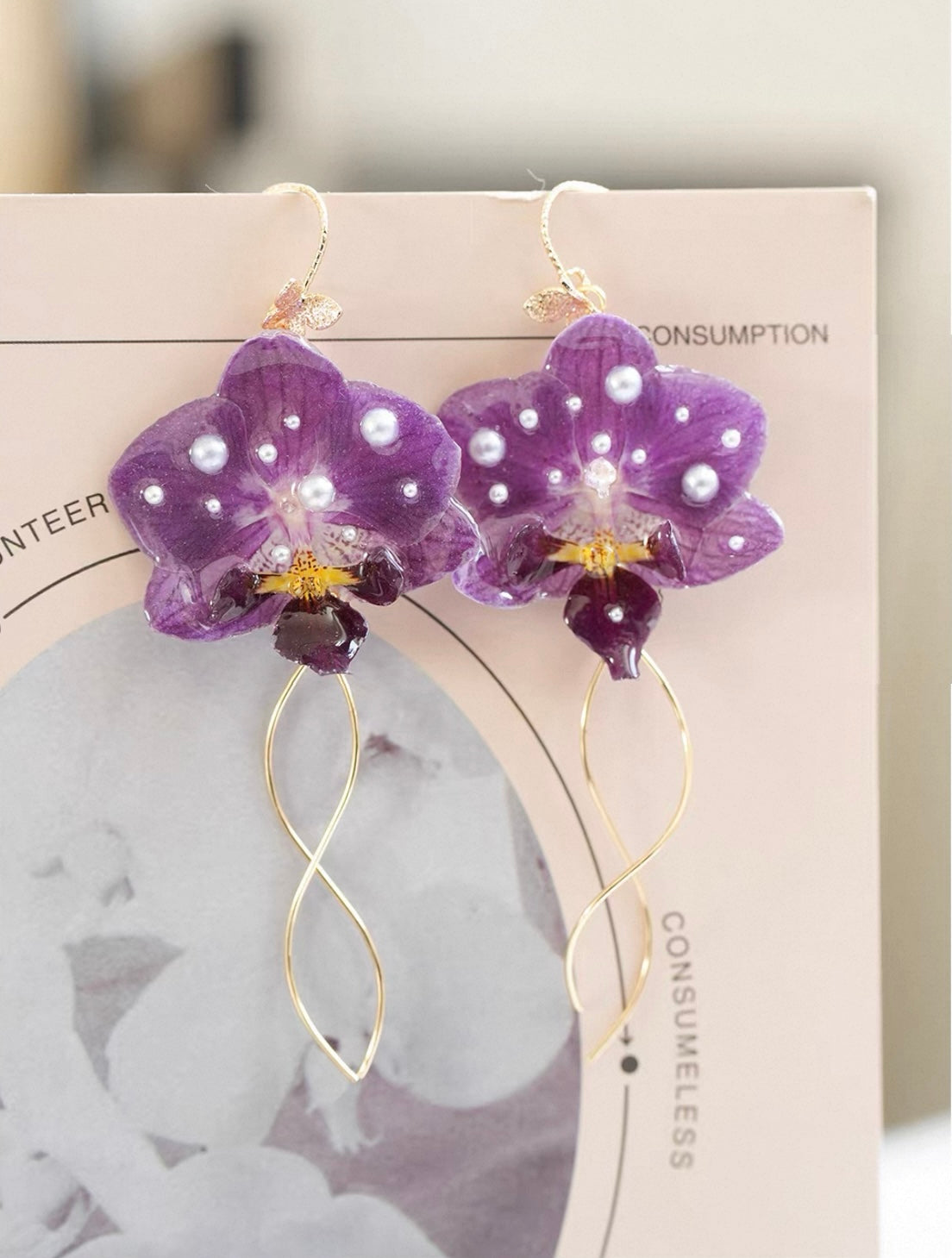 Purple orchid earrings with resin petals displayed on a jewellery card by Terra Decode