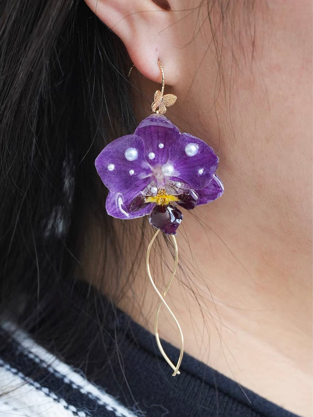 Purple orchid earrings with resin petals and fine tassel detail worn on ear by Terra Decode
