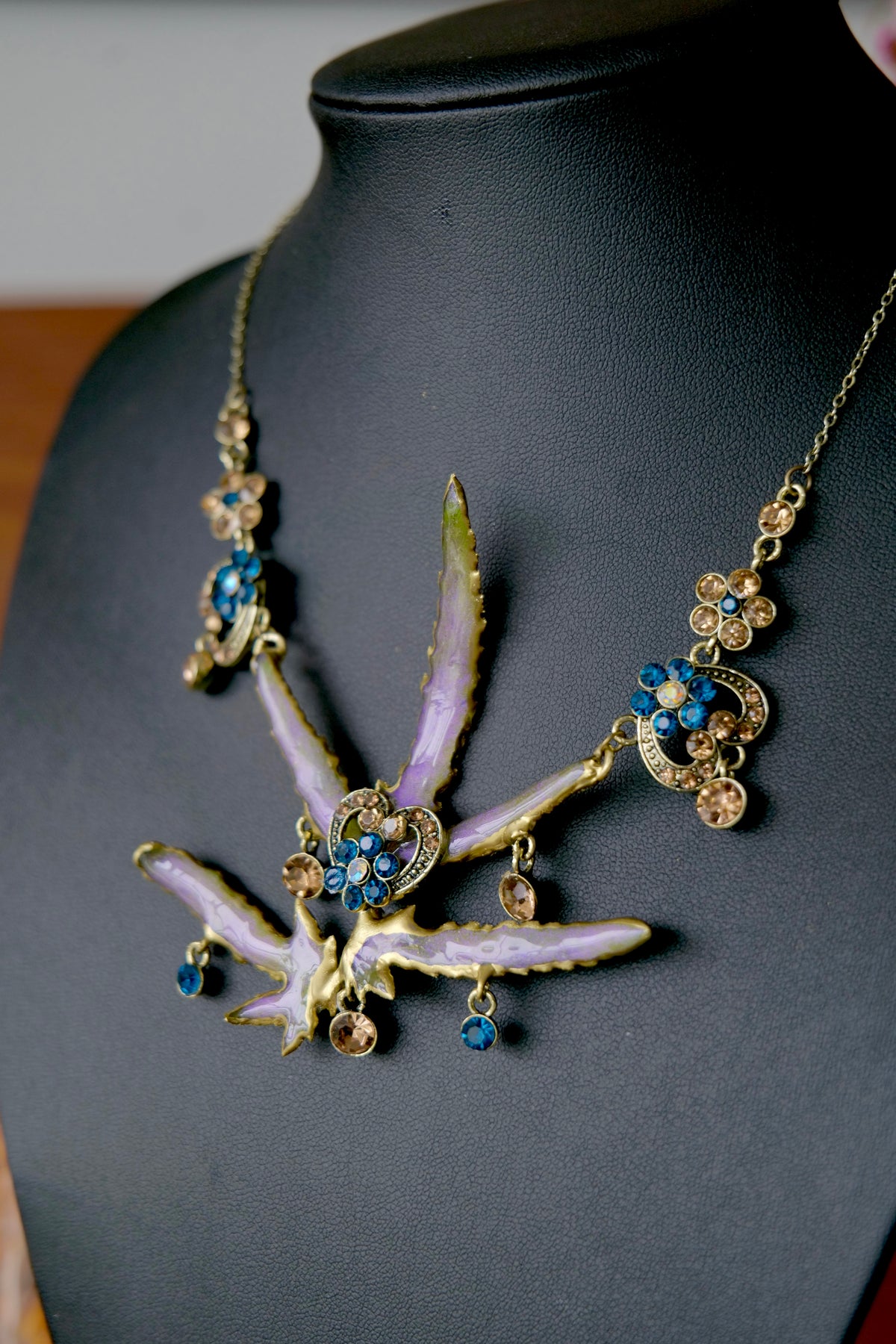 Vintage necklace featuring preserved Lygodium japonicum leaves, cobalt-blue crystals and antique-gold floral details.