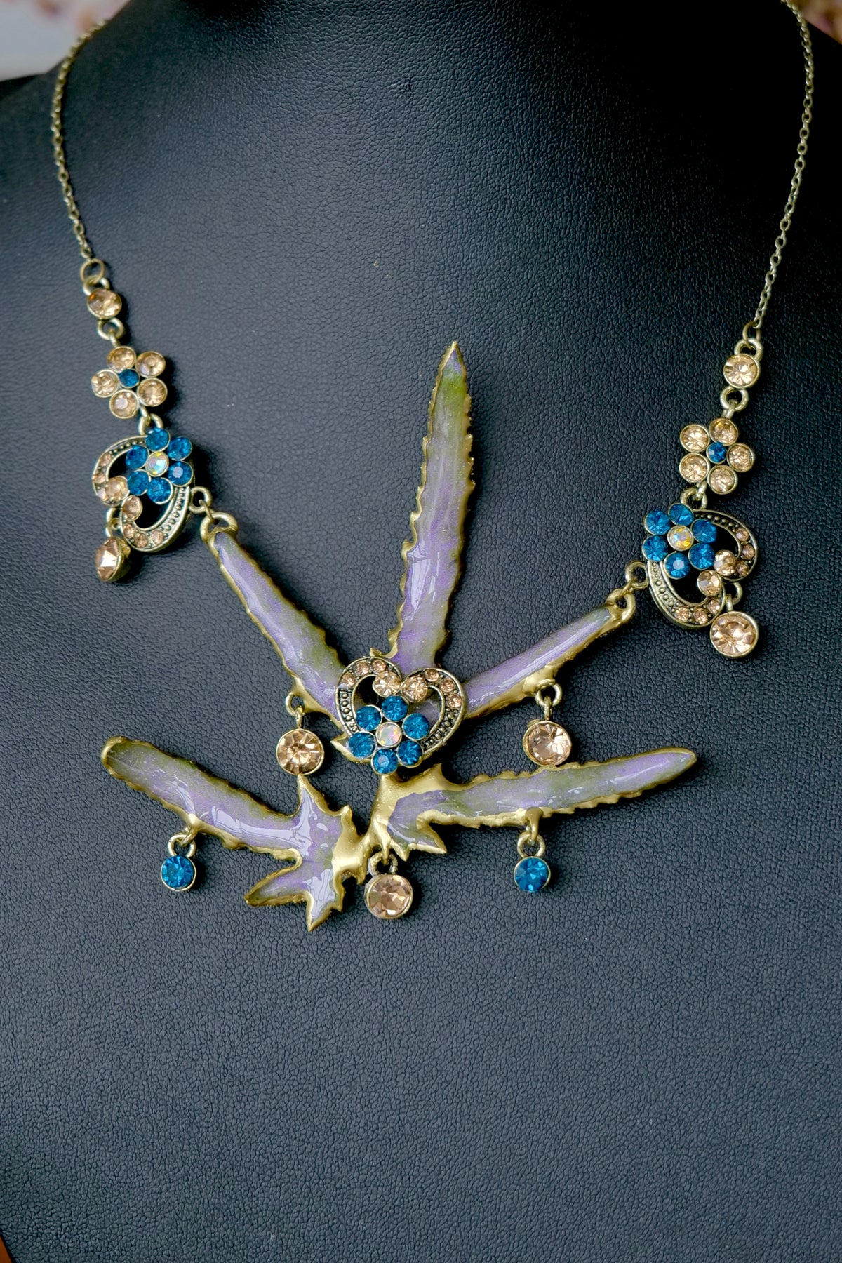 Side detail of a vintage-inspired Lygodium leaf necklace with cobalt-blue crystal drops.