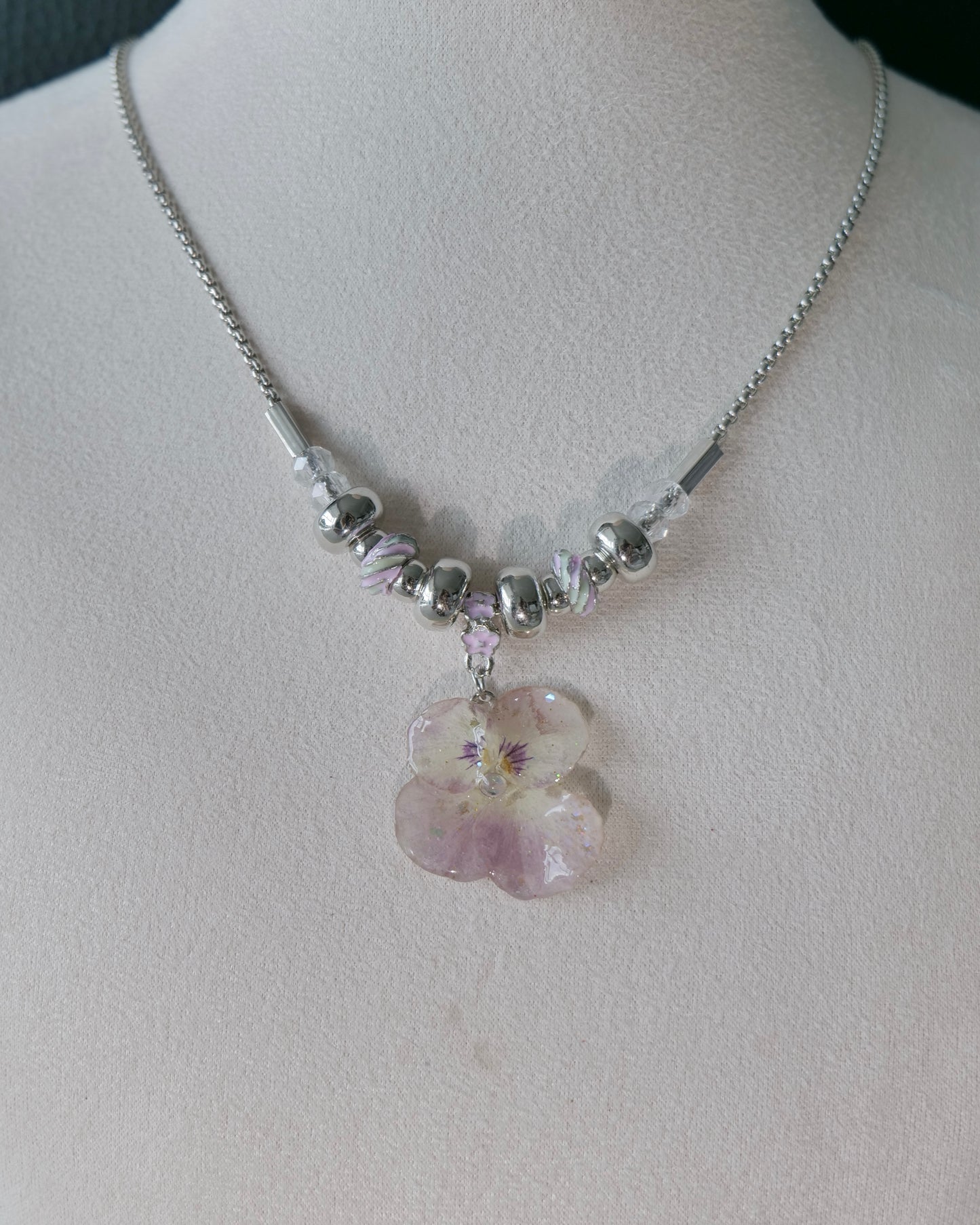 Natural-light view of preserved pink pansy necklace with clear faceted beads