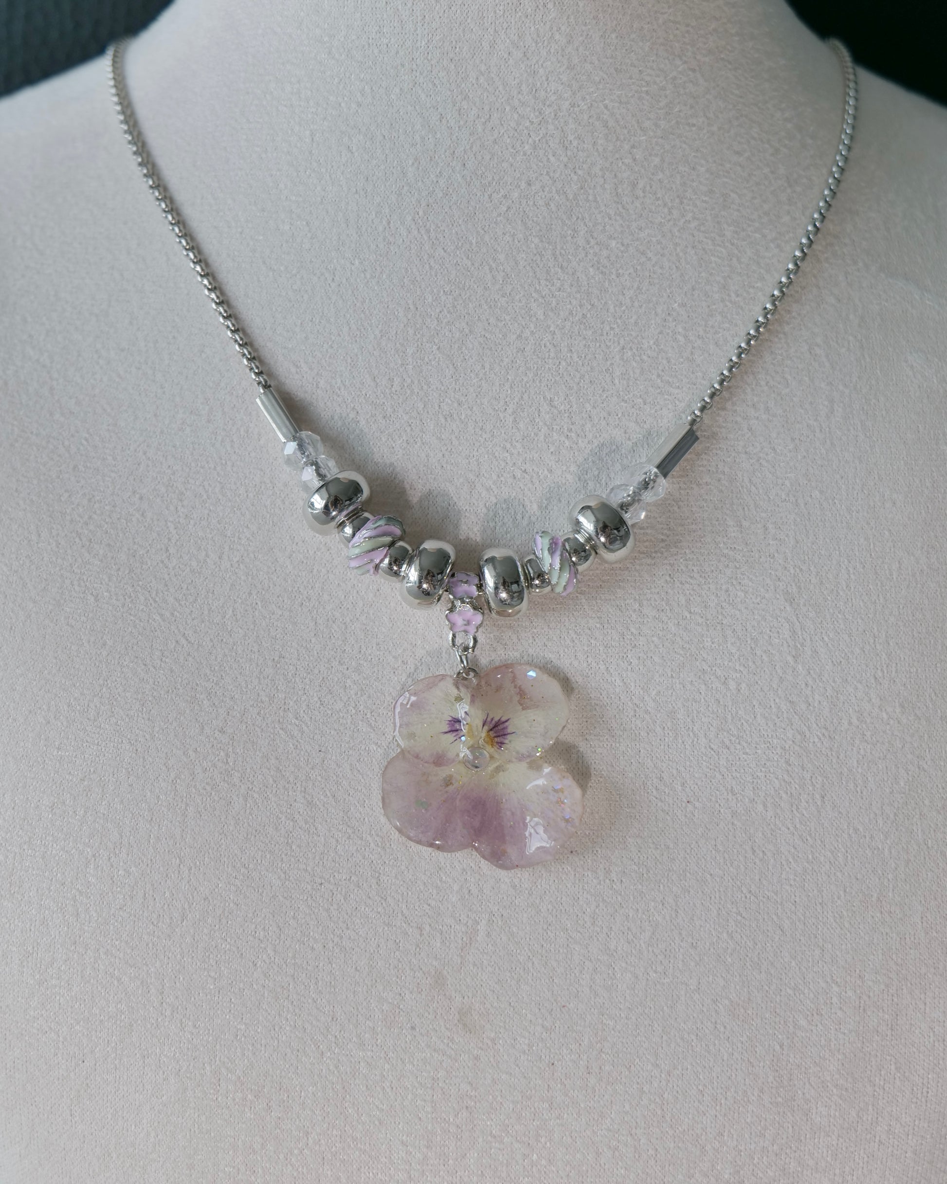 Natural-light view of preserved pink pansy necklace with clear faceted beads