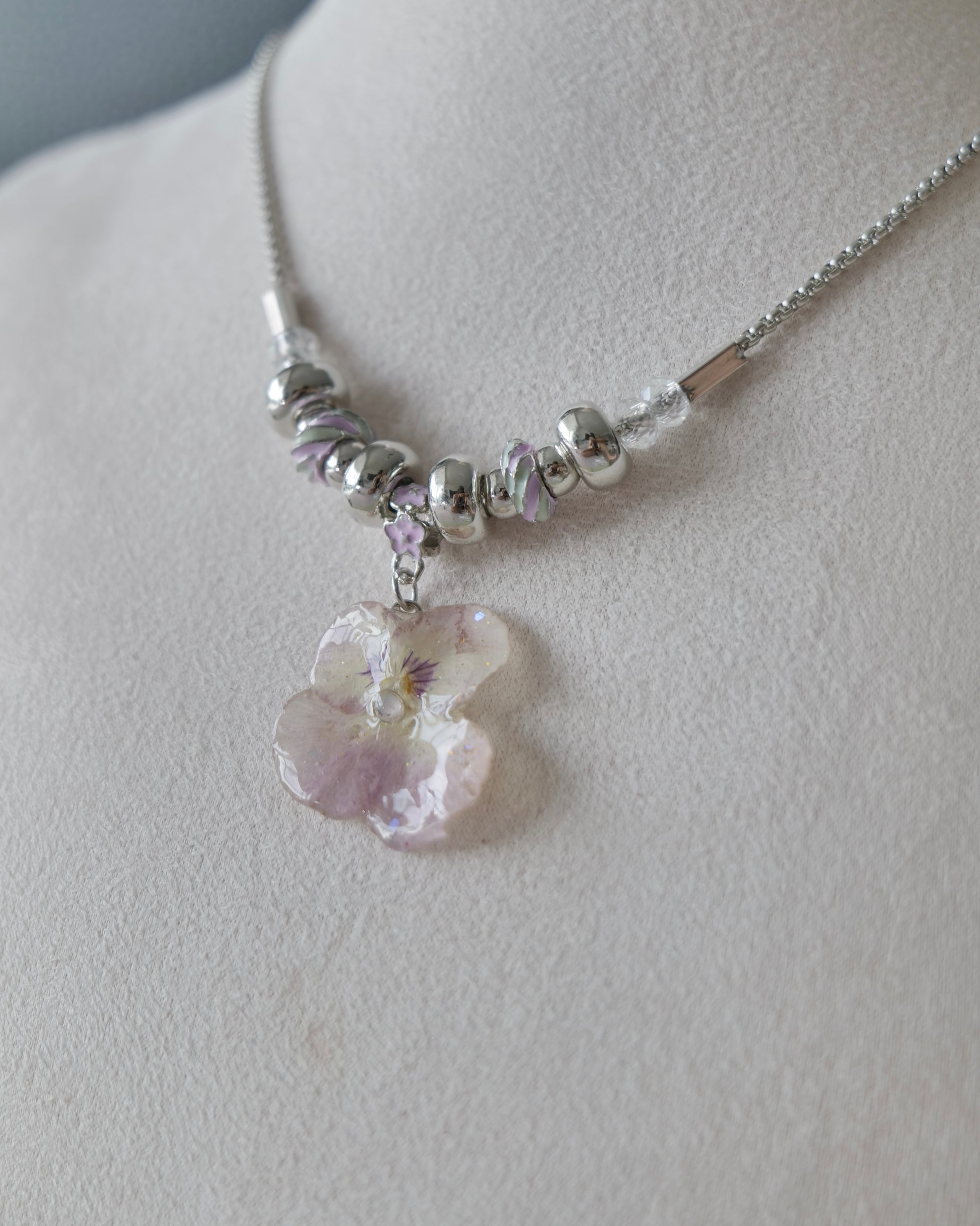 Angled view of the Smoky Pink Pansy Beaded Necklace showing its pastel bead pattern