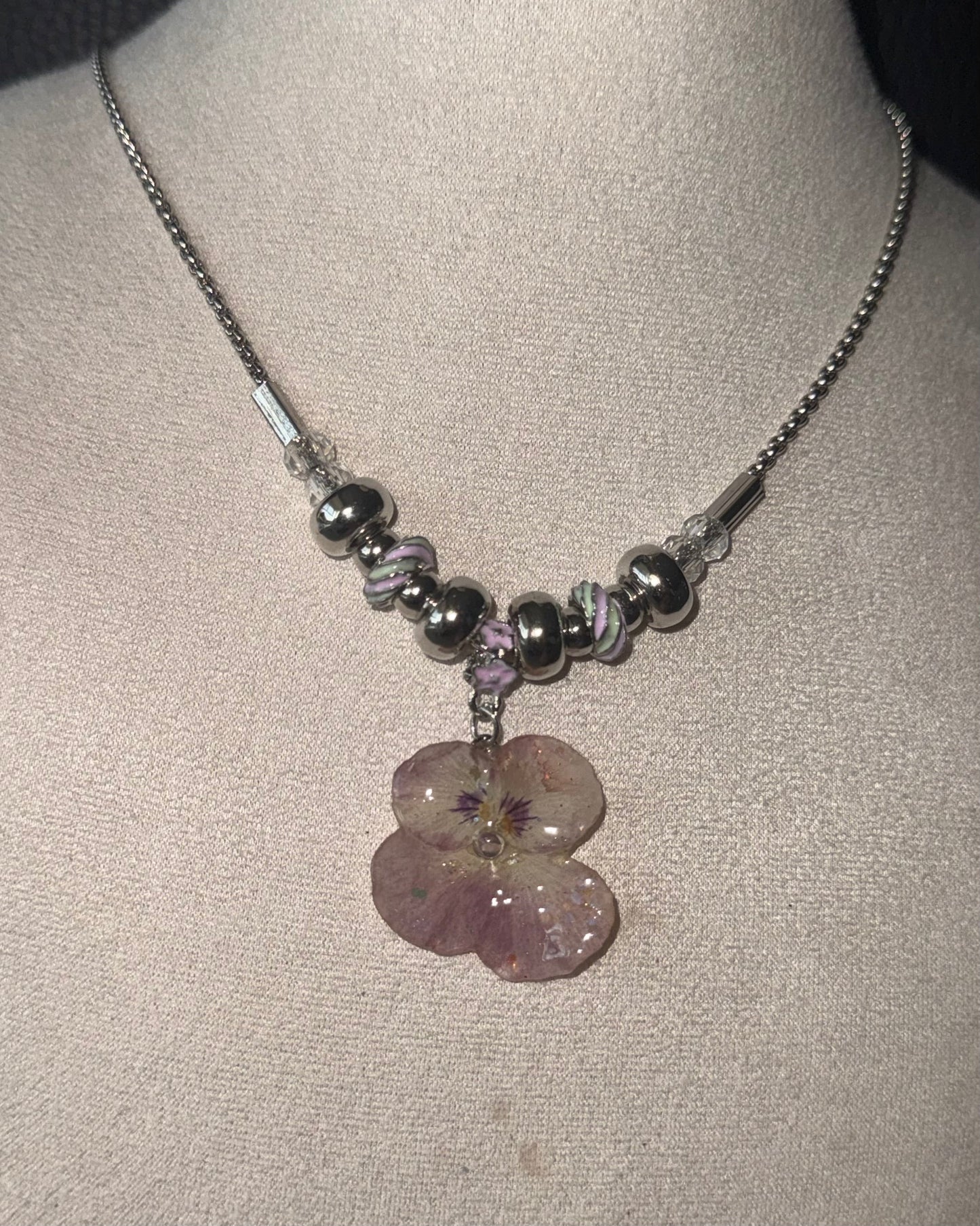 Reflective front view of smoky-pink pansy pendant with rounded beads