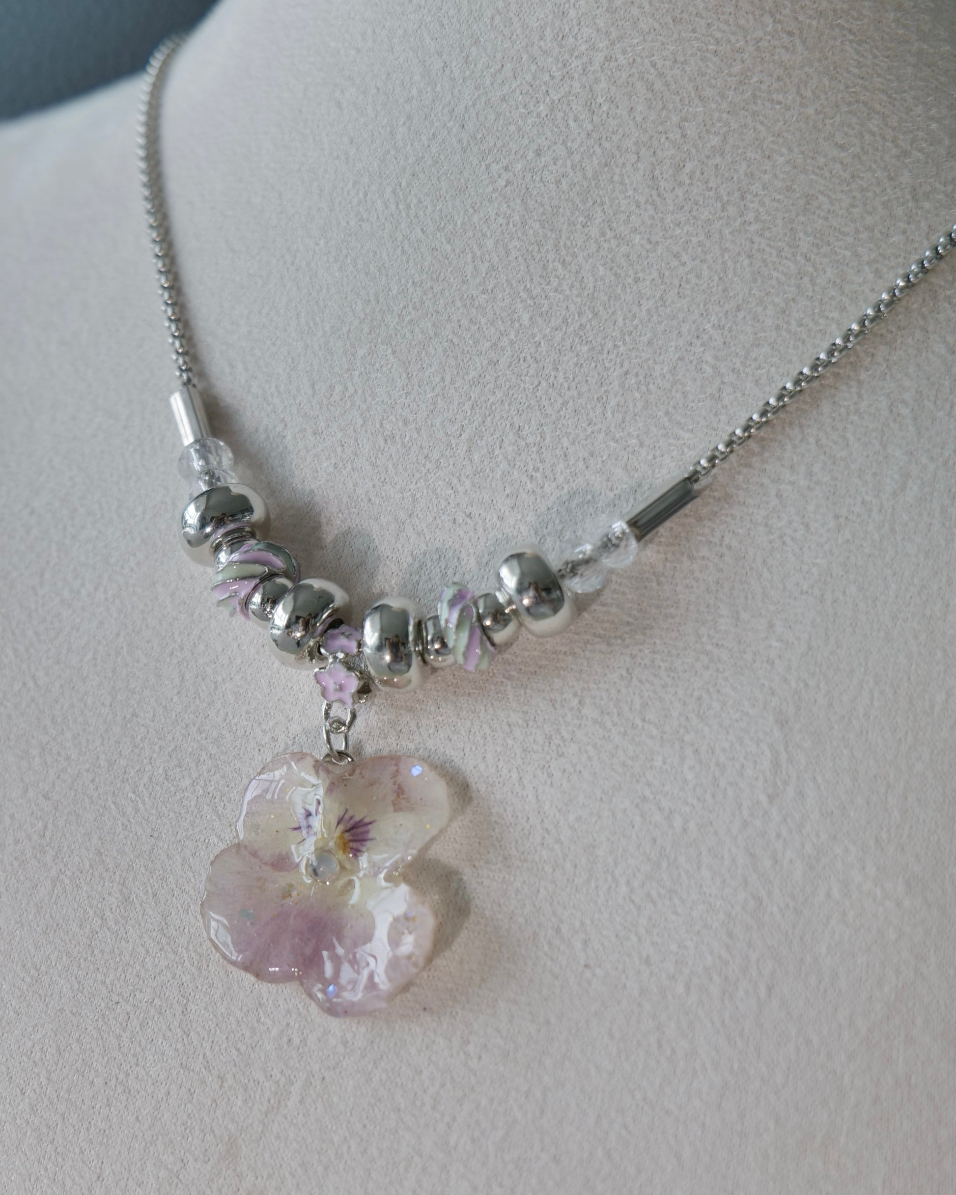 Detailed view of smoky-pink pansy pendant and alternating bead pattern