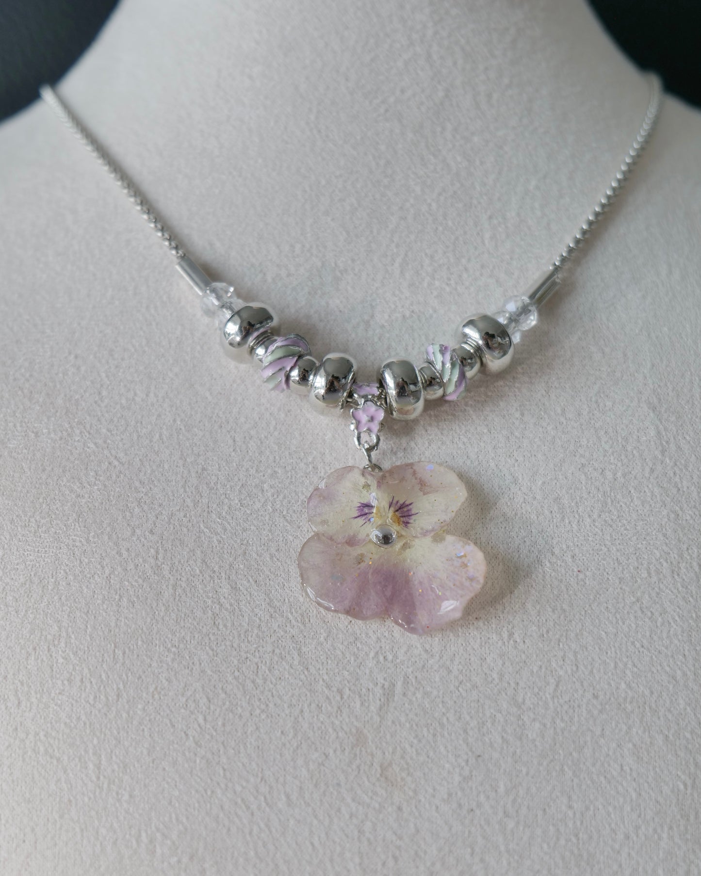 Front close-up of preserved smoky-pink pansy resin pendant
