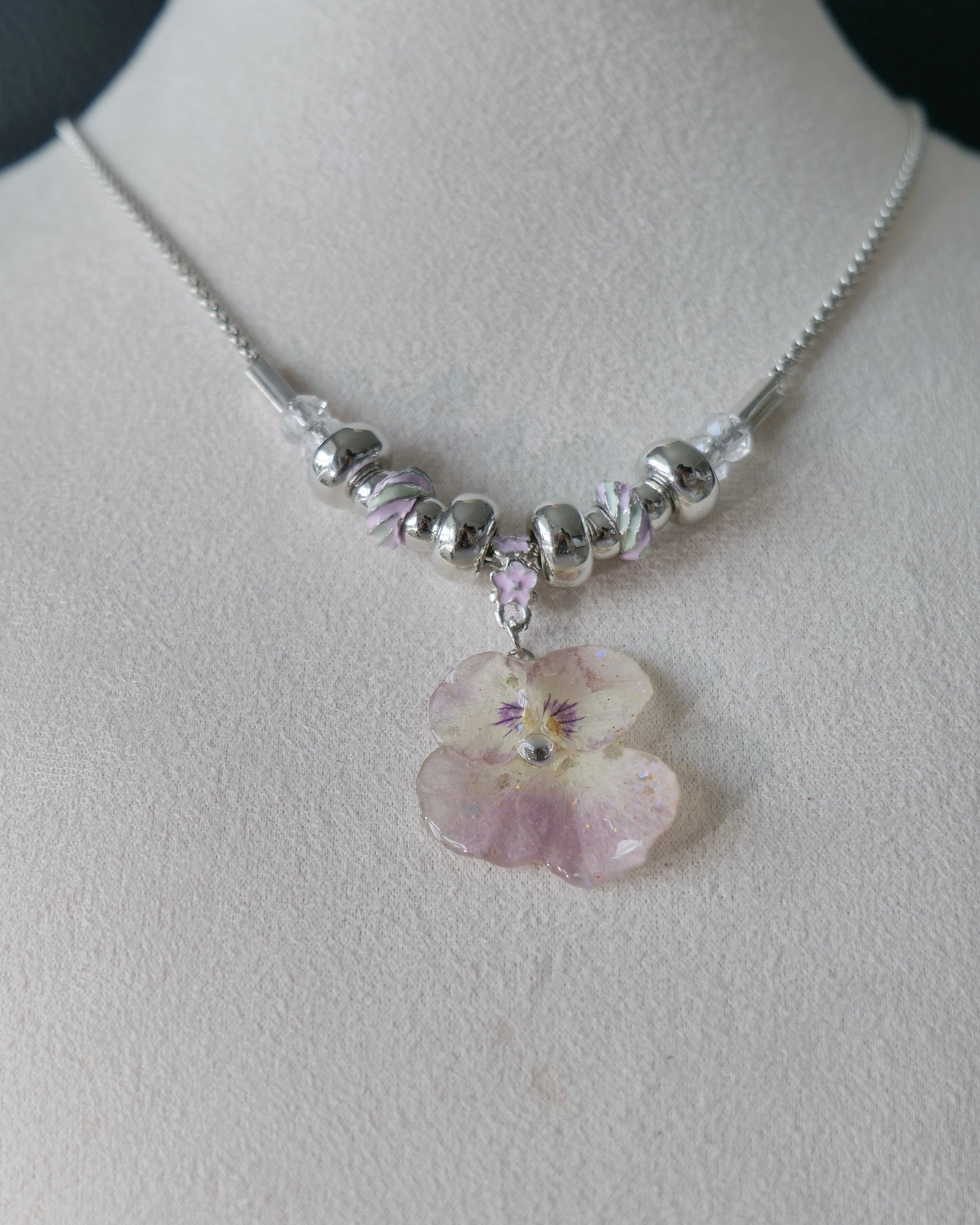 Front close-up of preserved smoky-pink pansy resin pendant