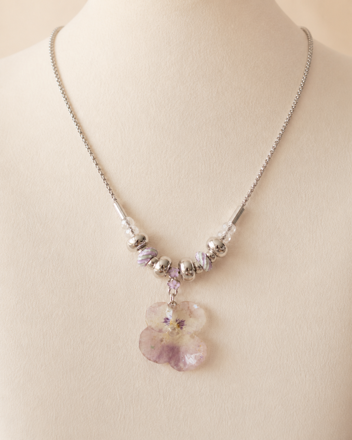 Angled view of the smoky-pink pansy pendant and silver-toned rounded beads, Smoky Pink Pansy Beaded Necklace botanical jewellery by Terra Decode