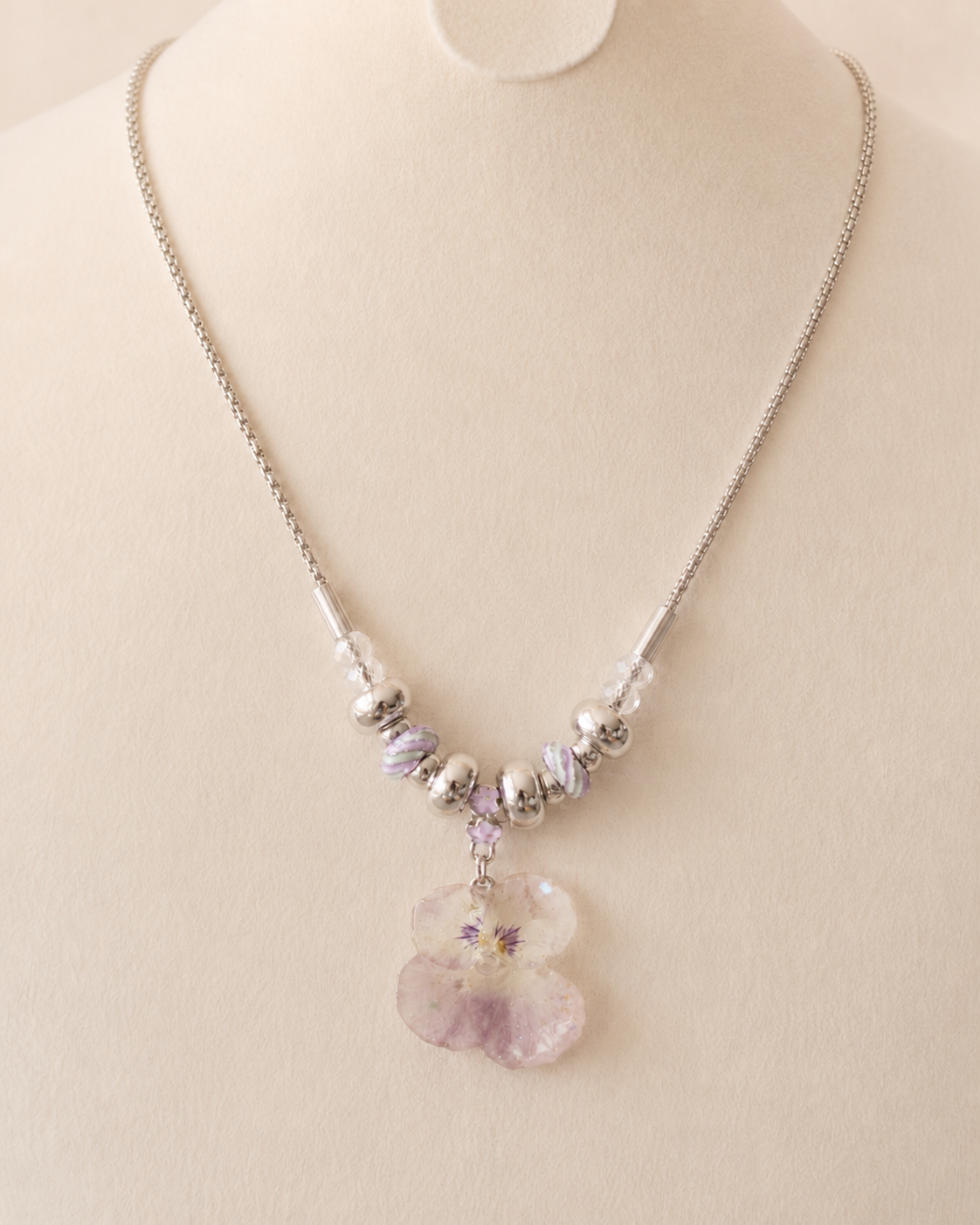 Detailed view of the pink and lilac bead pattern on a cream jewellery bust, Smoky Pink Pansy Beaded Necklace botanical jewellery by Terra Decode