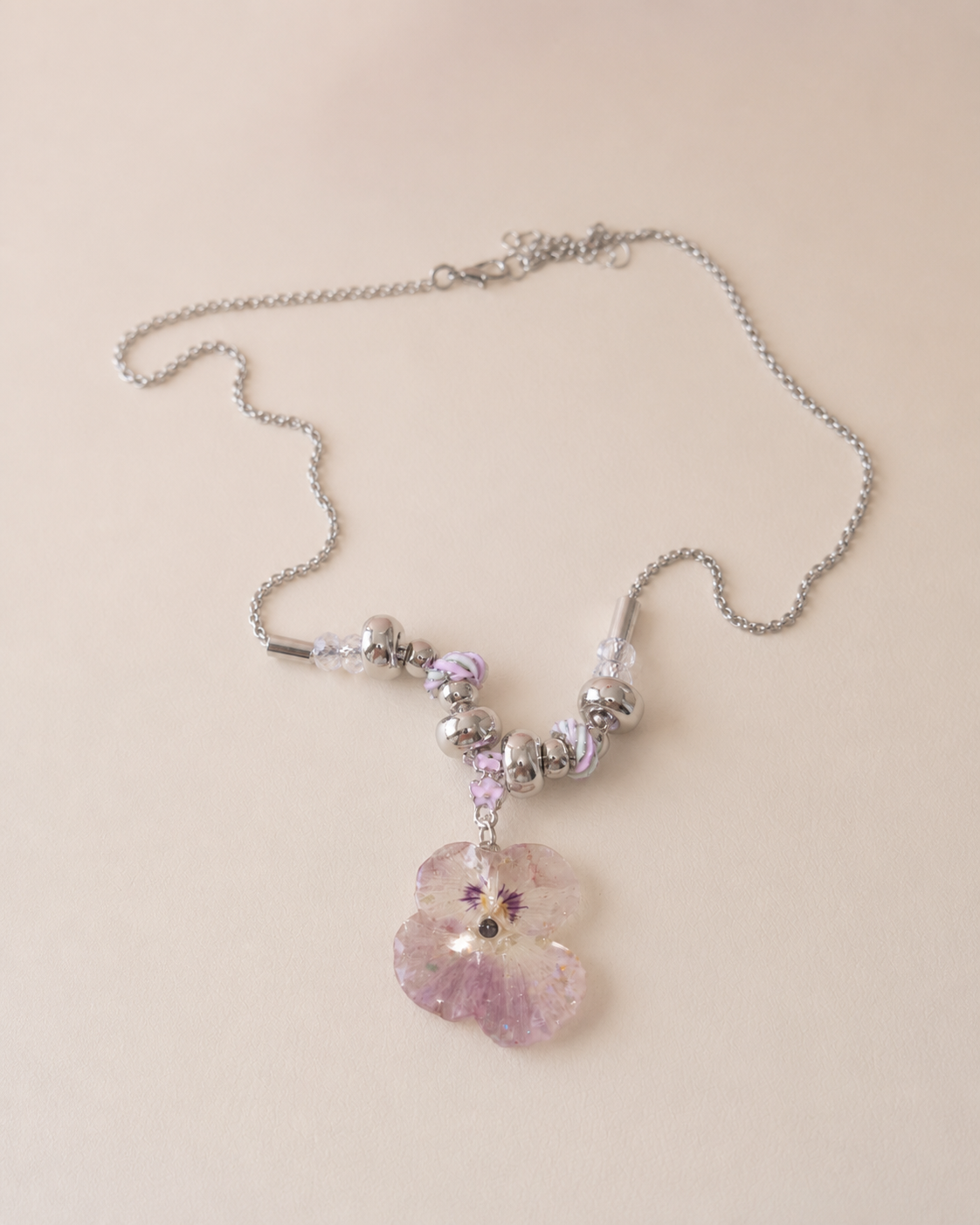 Reflective detail of the smoky-pink pansy necklace and silver-toned beads, Smoky Pink Pansy Beaded Necklace botanical jewellery by Terra Decode