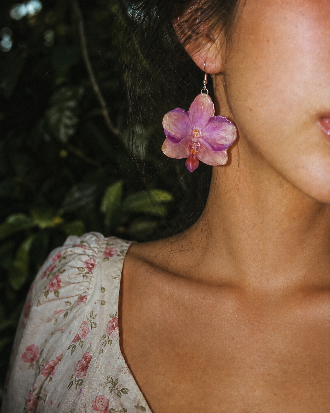 Flash portrait showing the translucent pink-purple orchid earring and silver-tone hook, Sunset Pink Phalaenopsis Drop Earrings botanical jewellery by Terra Decode