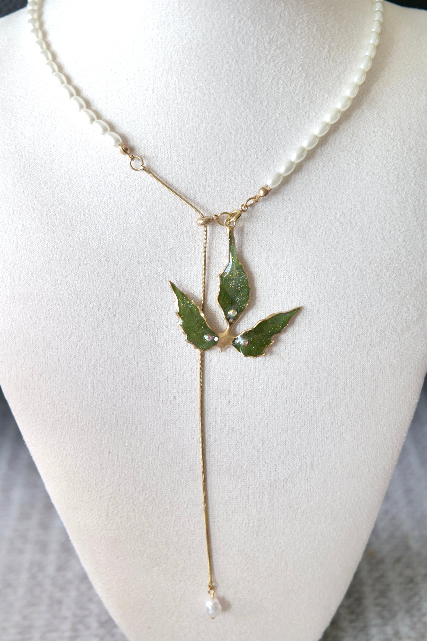 Side view of the clear-resin Boston ivy pendant and gold-toned edging