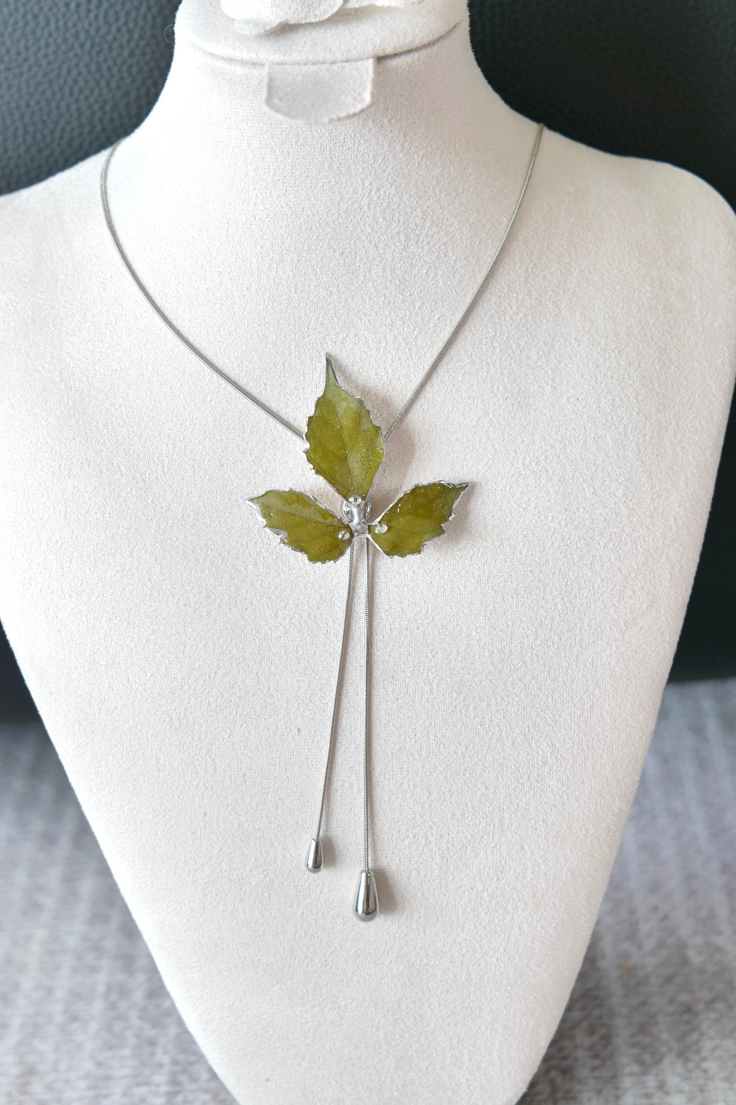 Close-up of preserved Boston ivy leaves framed by silver-toned alloy metal