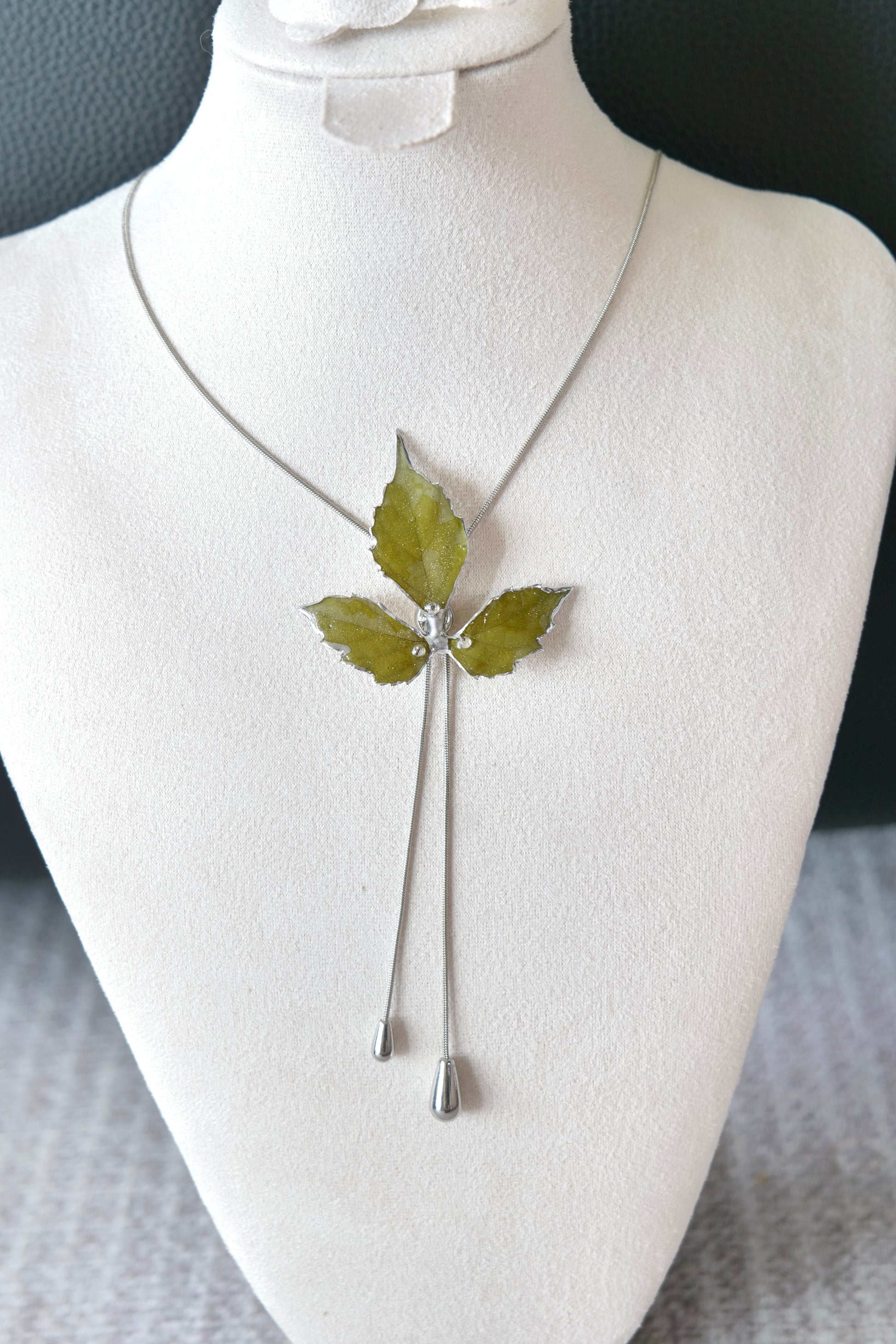 Close-up of preserved Boston ivy leaves framed by silver-toned alloy metal