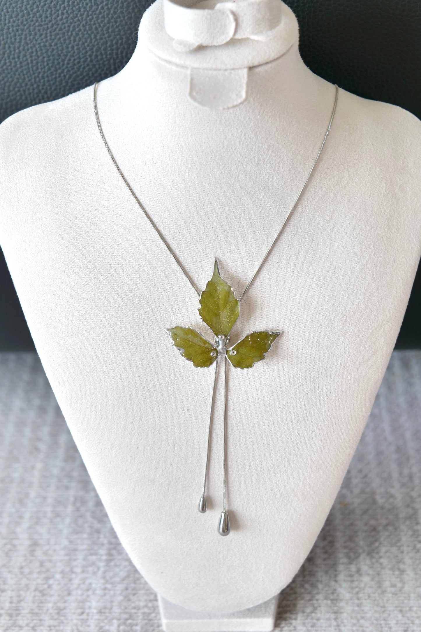 Twin polished metal drops below the clear-resin Boston ivy pendant
