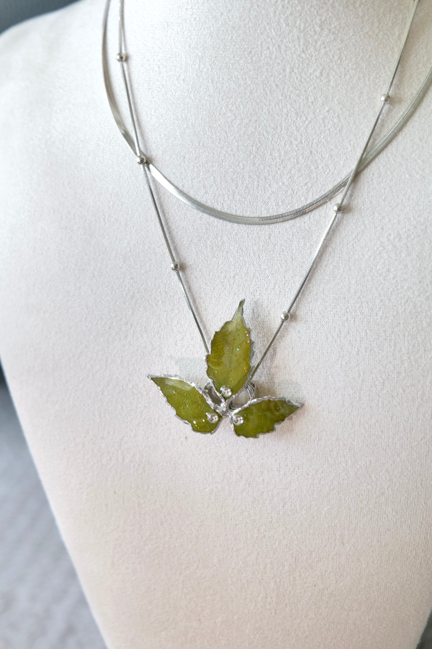 Right angled view of the layered silver three-leaf botanical necklace by Terra Decode