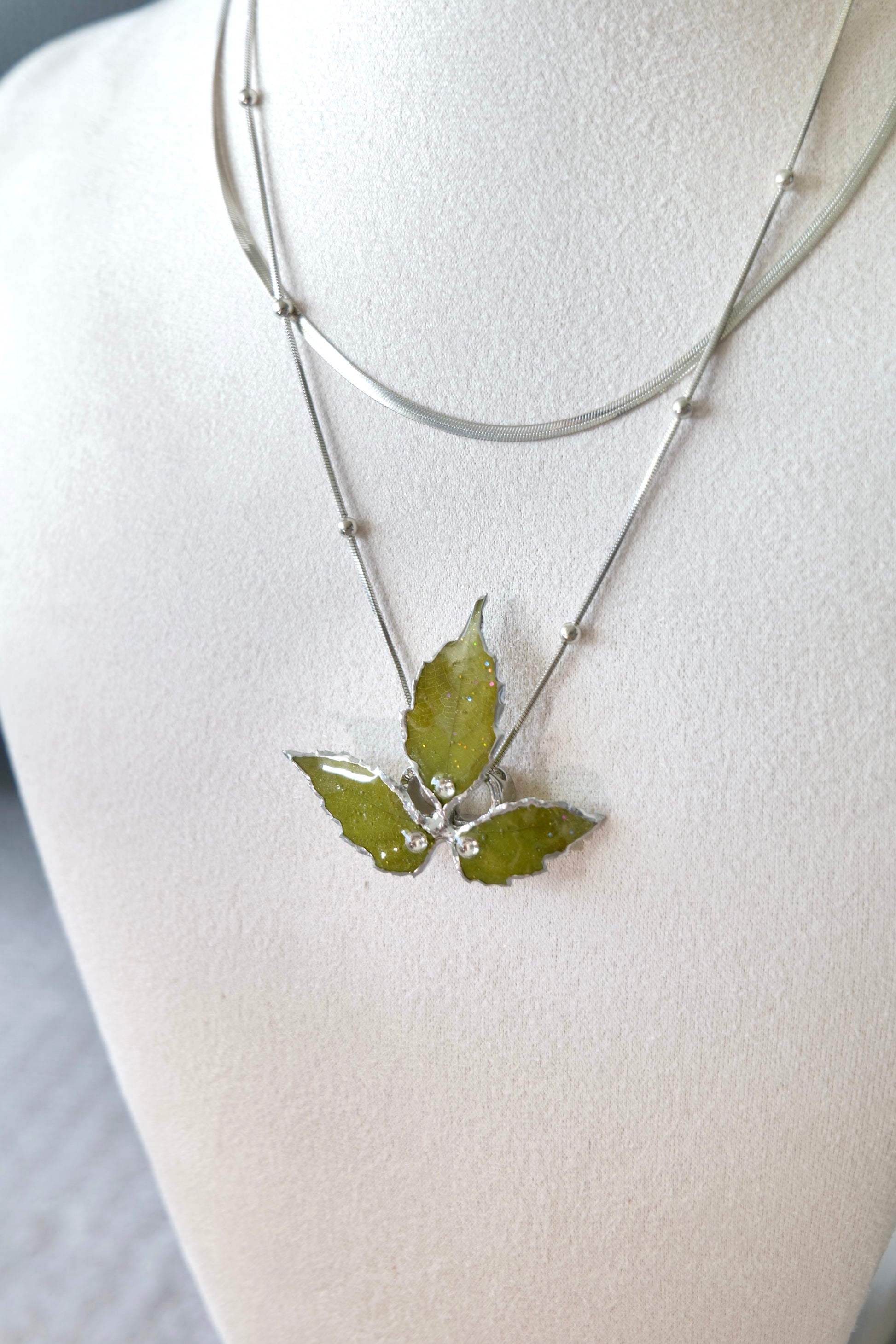 Pendant close-up of the layered silver three-leaf botanical necklace by Terra Decode