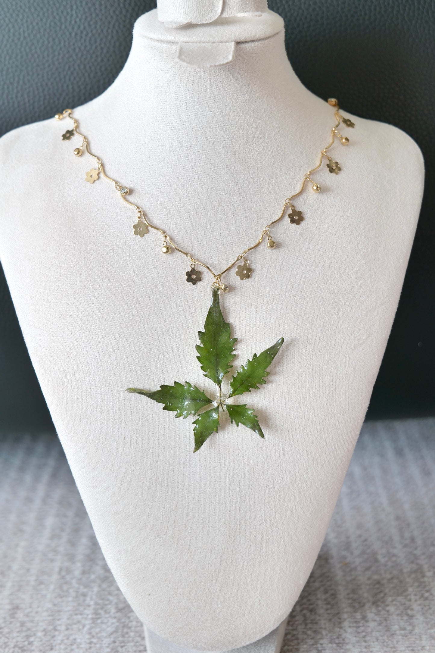 Left angled view of the serrated five-leaf floral-charm necklace by Terra Decode