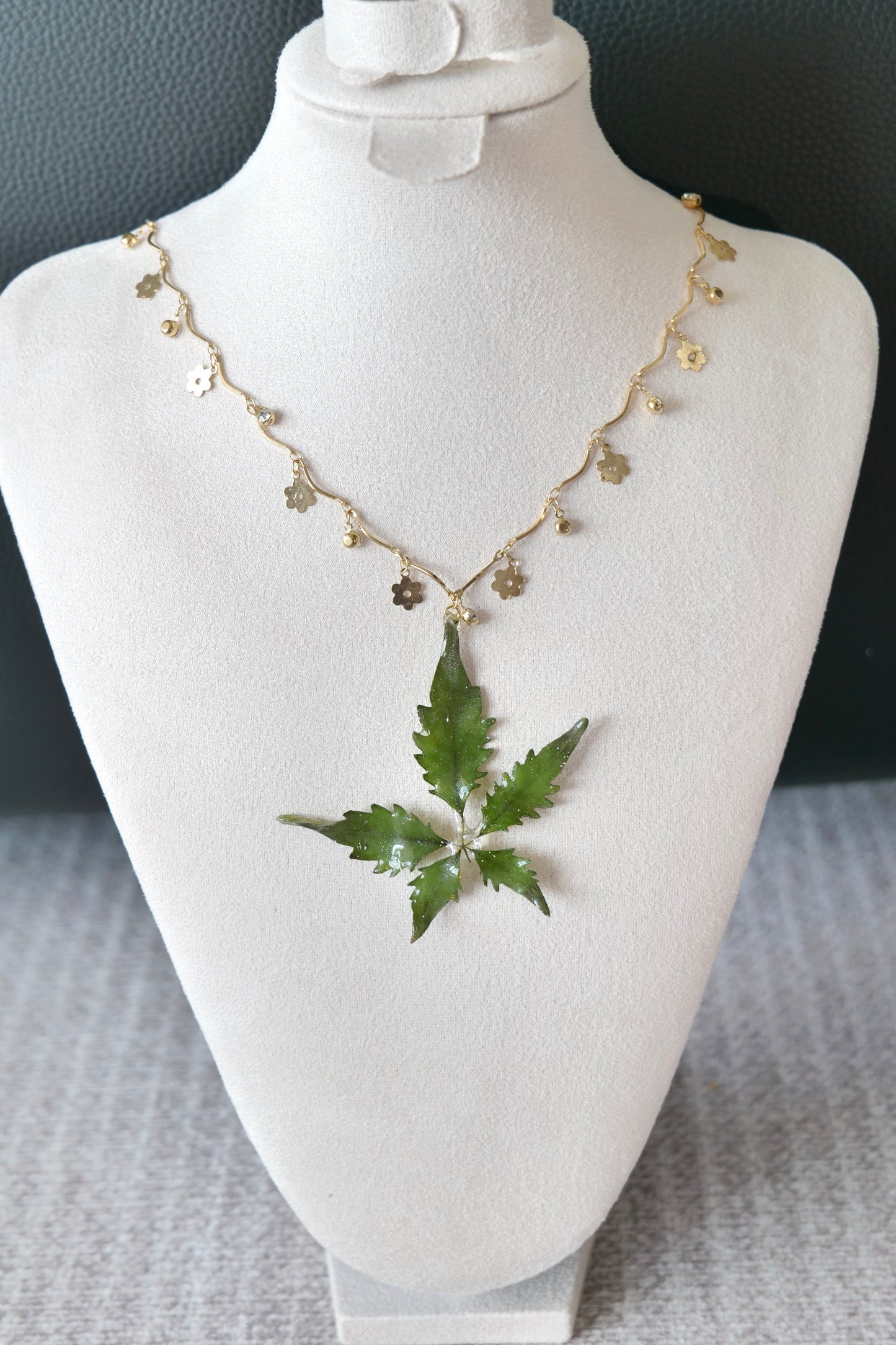 Right angled view of the serrated five-leaf floral-charm necklace by Terra Decode