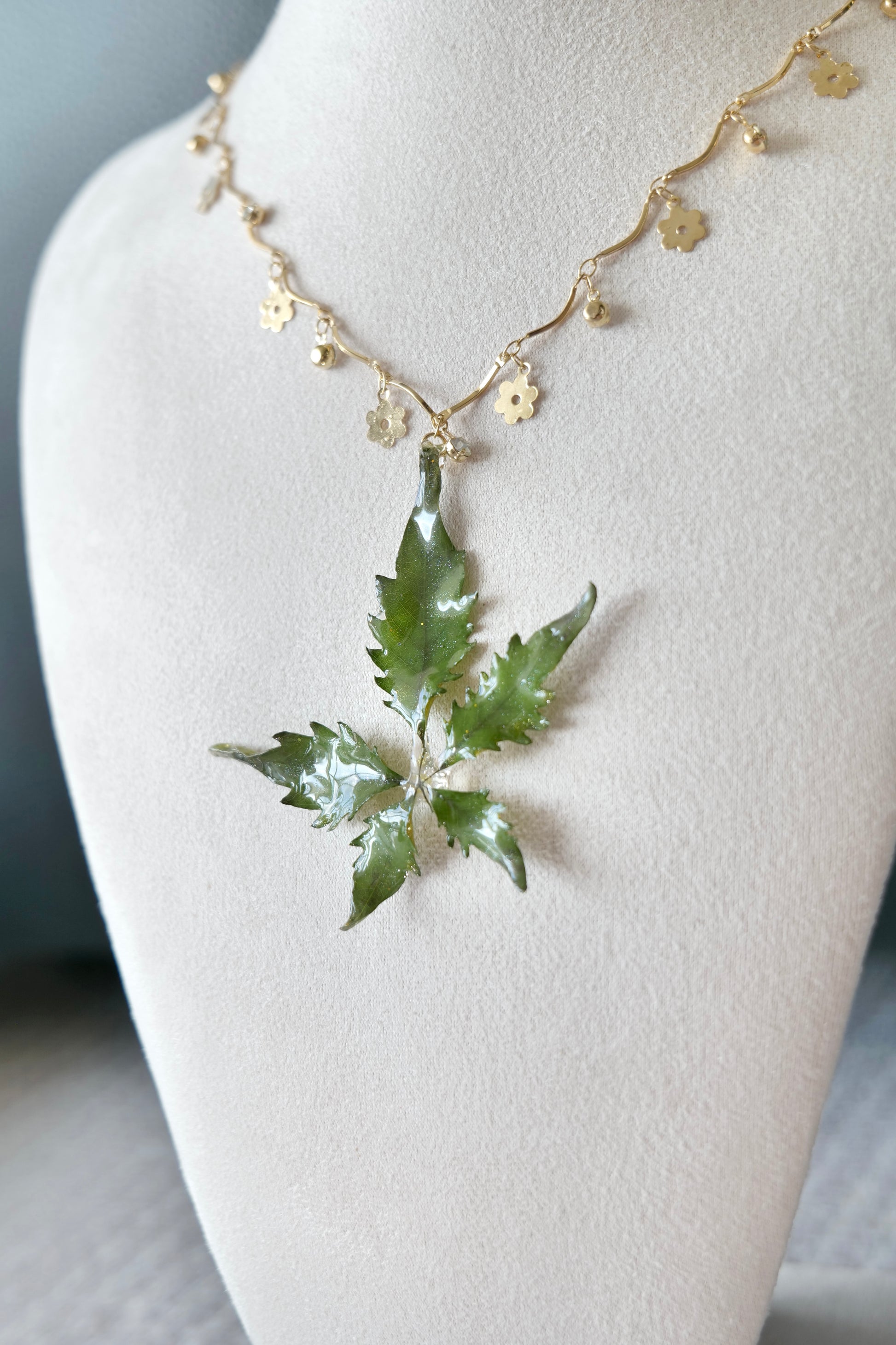 Floral charm chain detail below the preserved botanical pendant